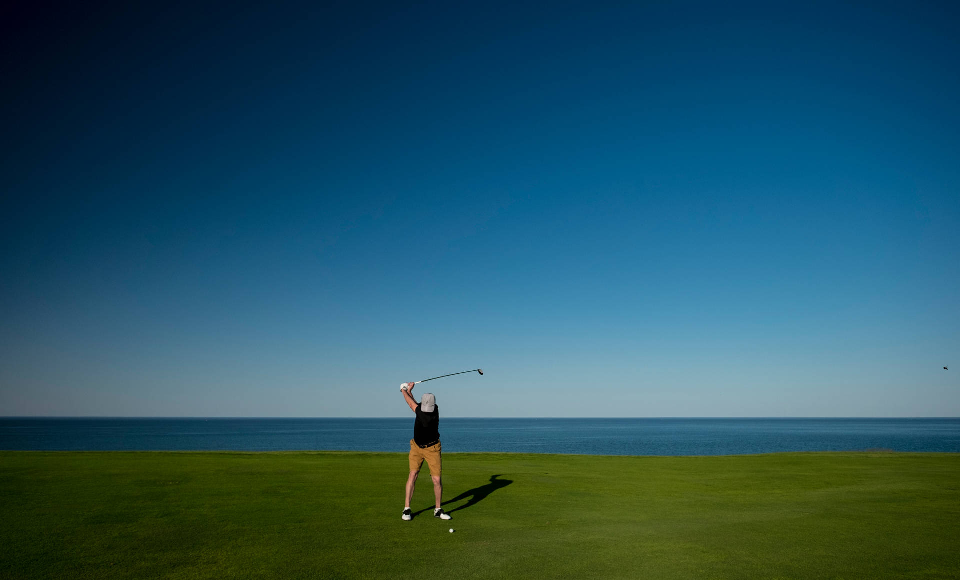 Man Swinging On Golf Course By Sea Background