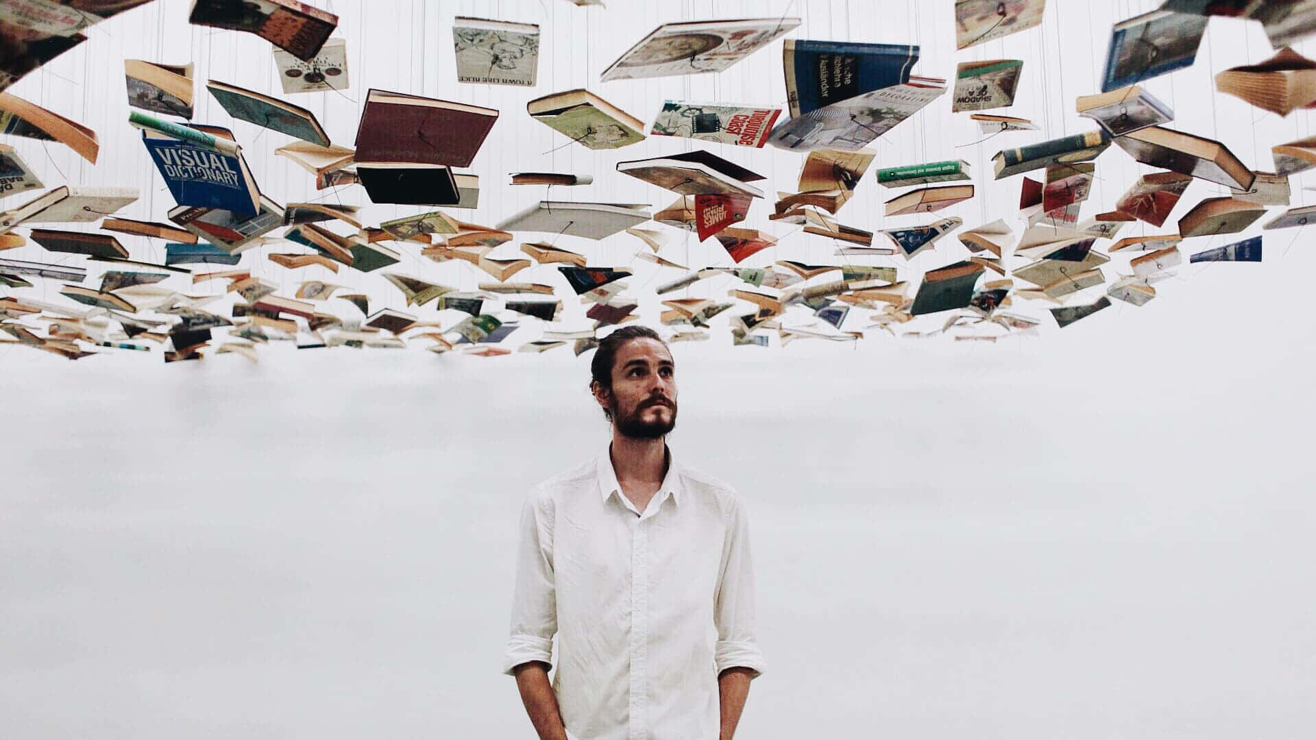 Man Under Floating Books