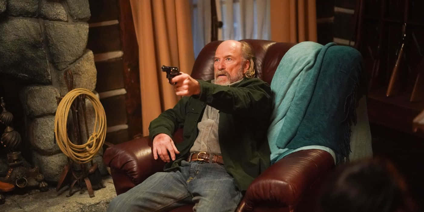 Man With Gun Seatedin Armchair Background