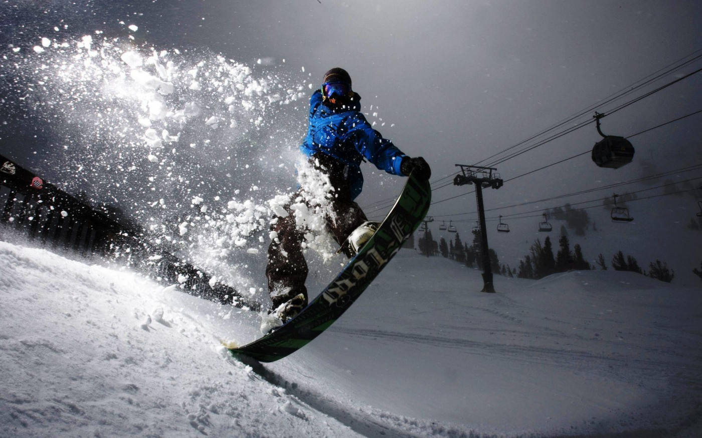 Man With Snowboard And Cable Cars Behind Him