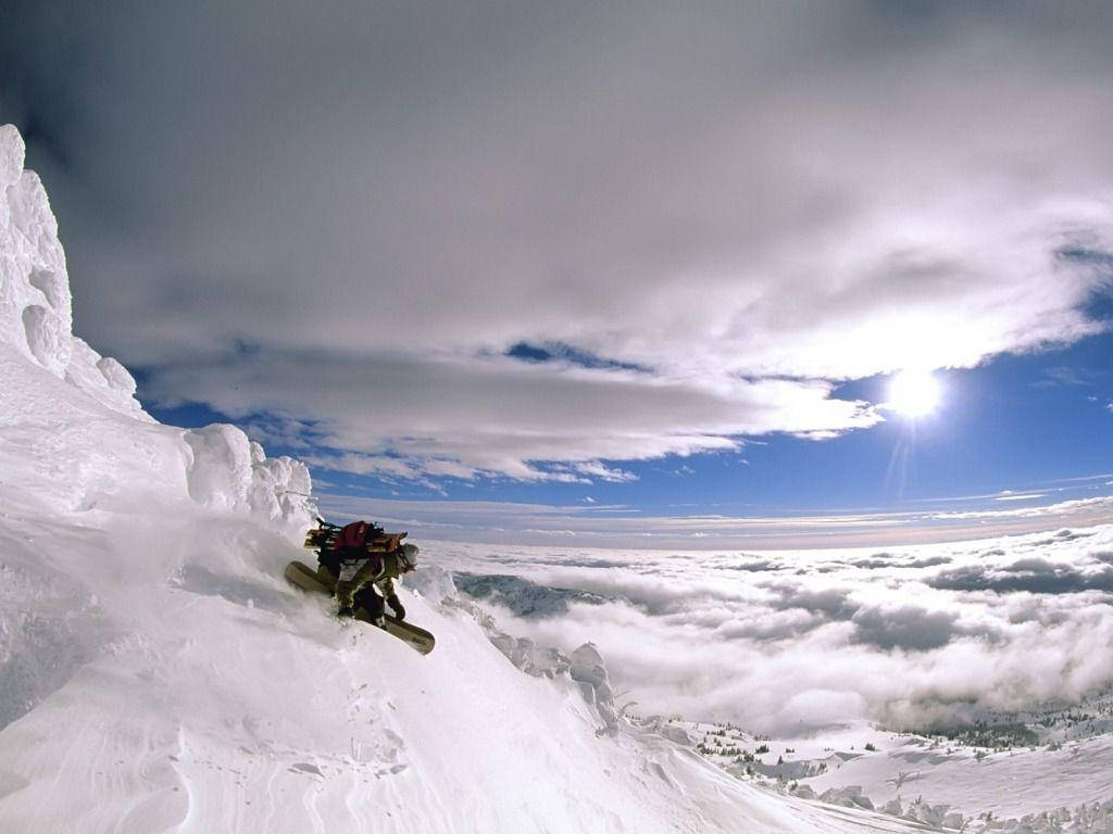 Man With Snowboard Dashes Down A Mountain Background