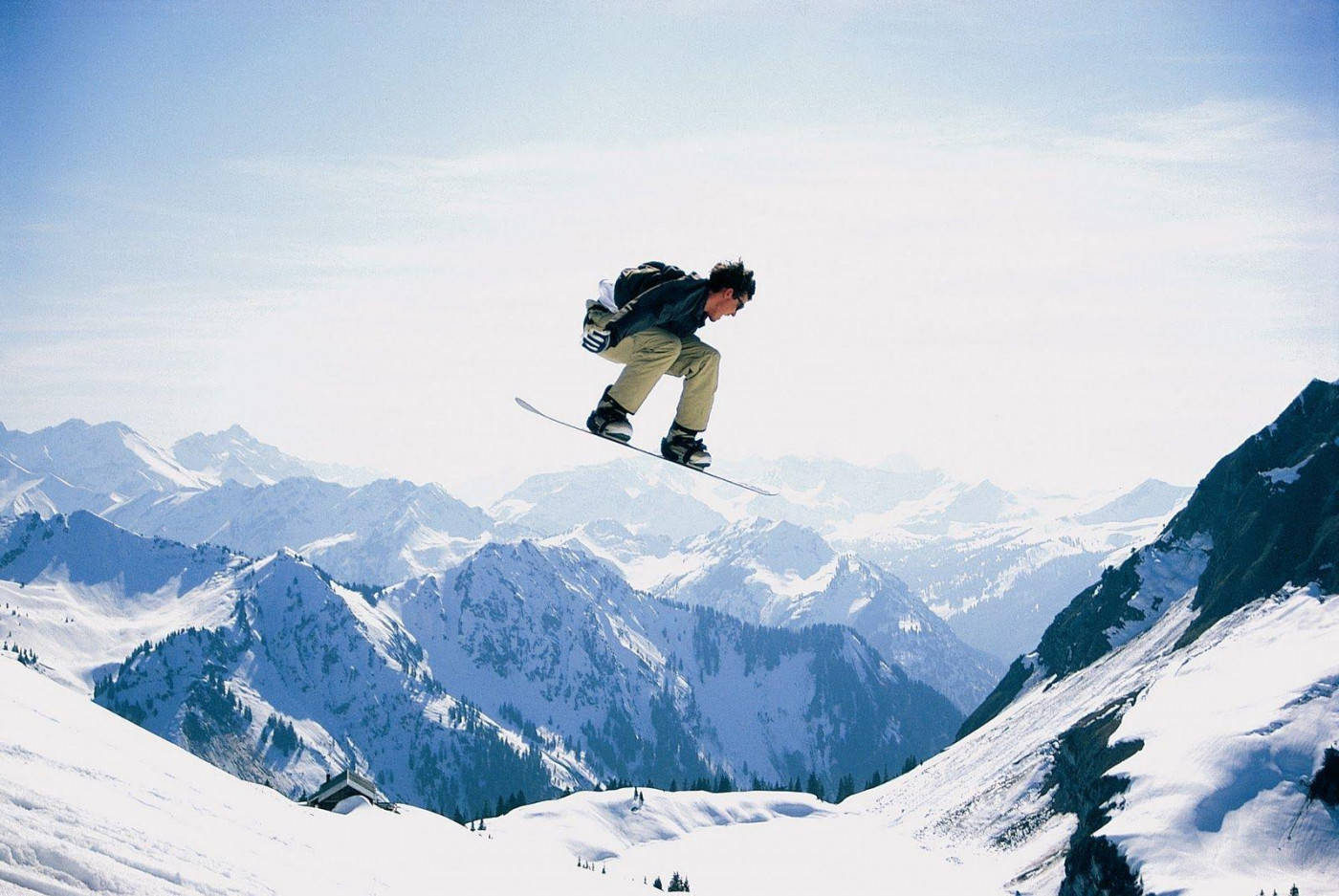 Man With Snowboard Descending With Mountainous Backdrop