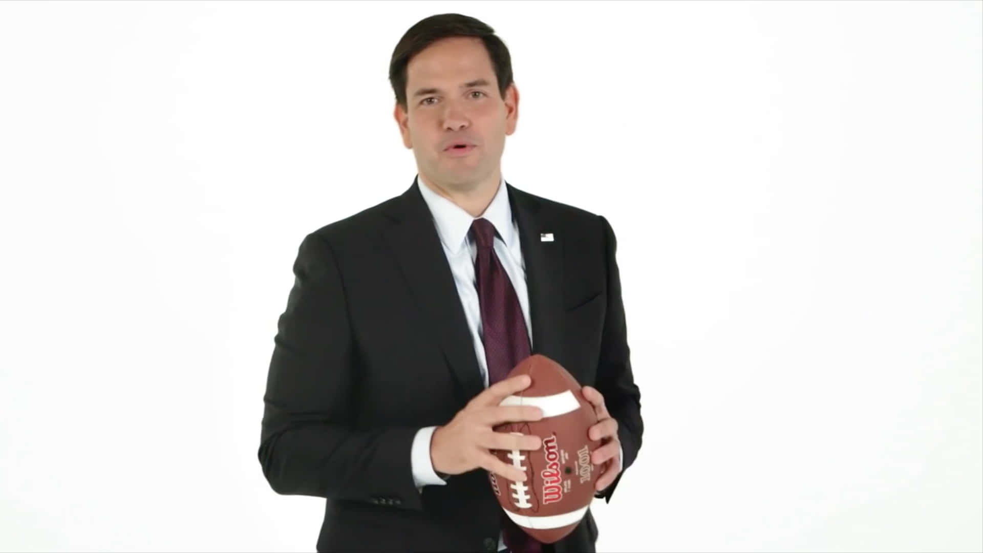 Marco Rubio Holding A Football Background