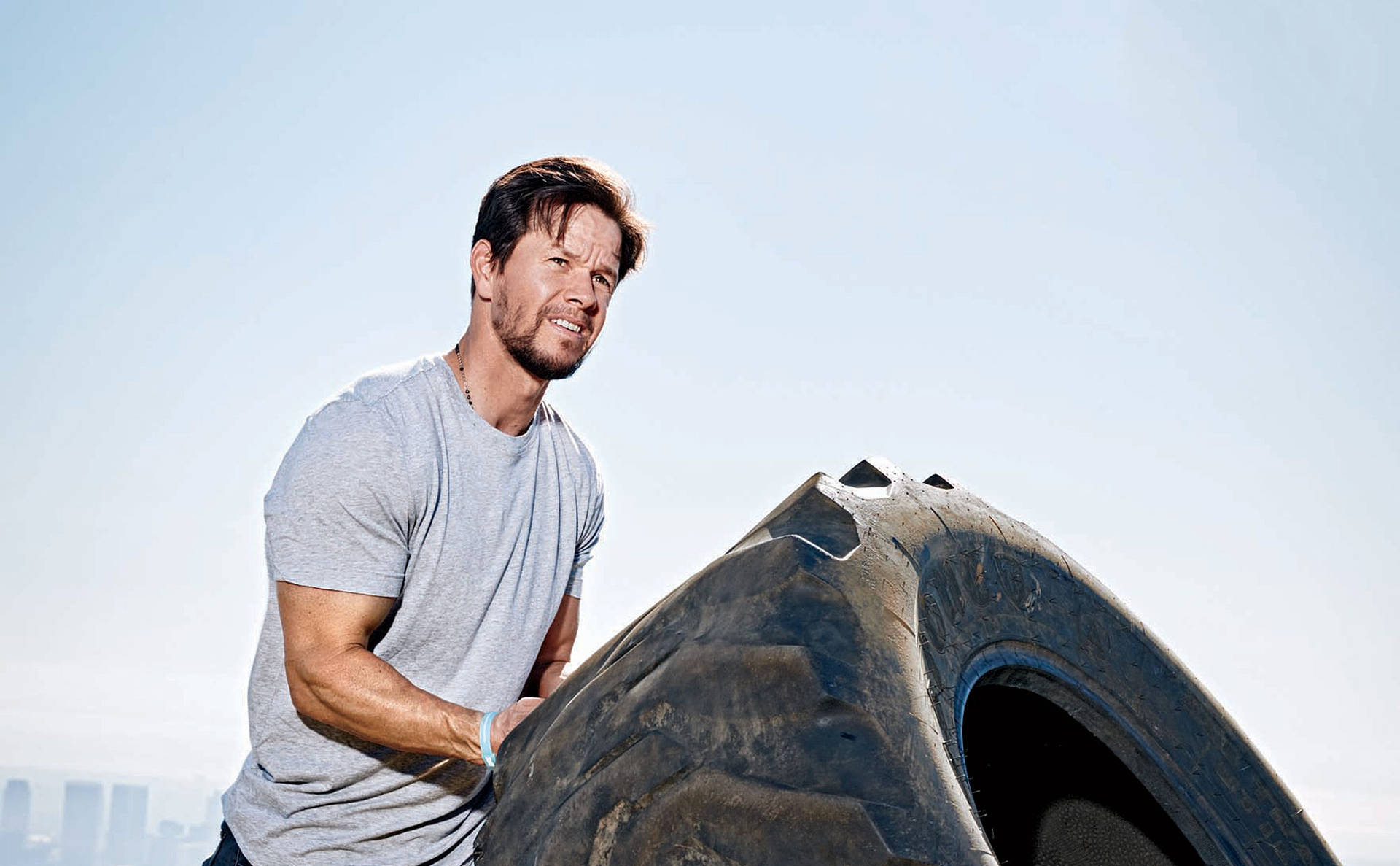 Mark Wahlberg Lifting A Tire Background