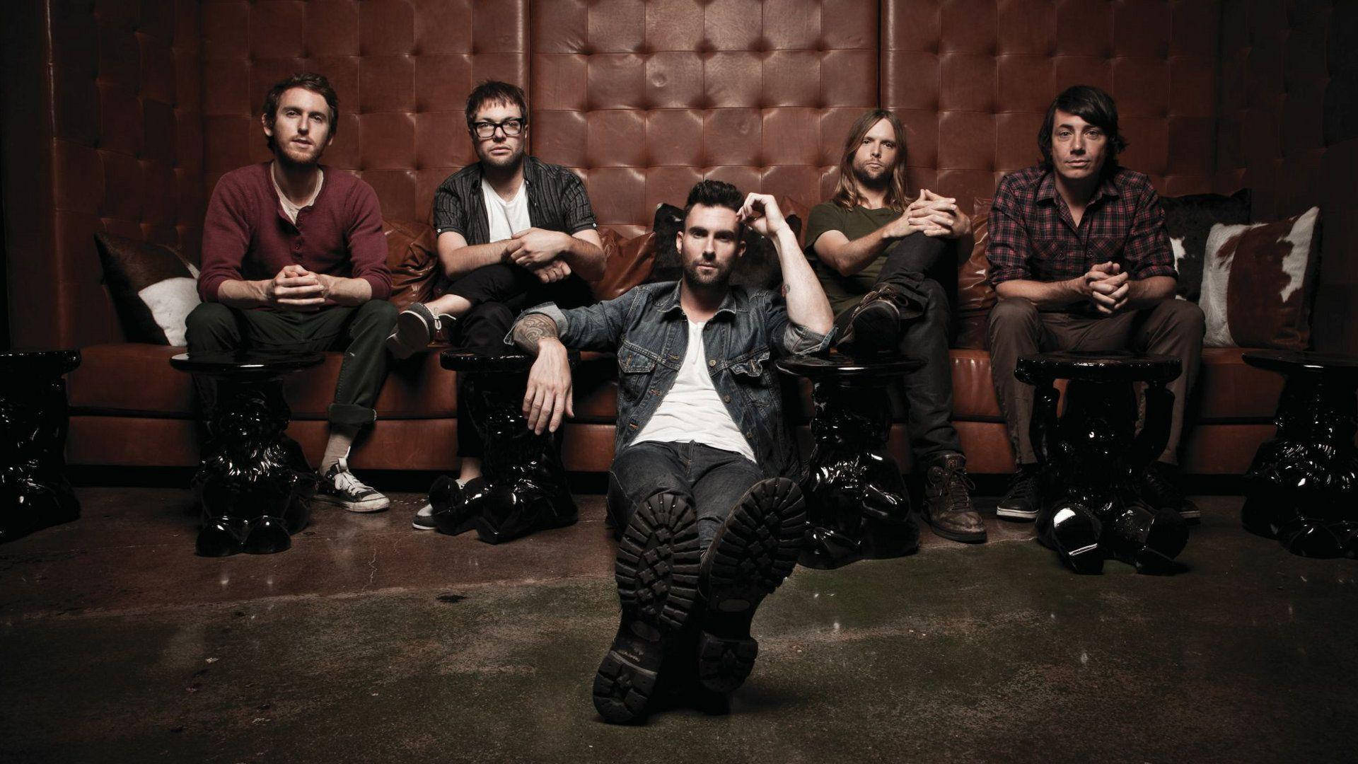 Maroon 5 Resting Brown Sofa Background