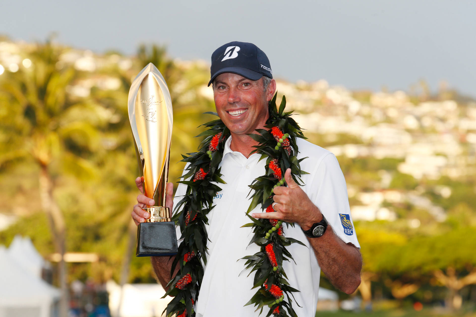 Matt Kuchar Celebrating Championship Victory With Garland And Trophy Background