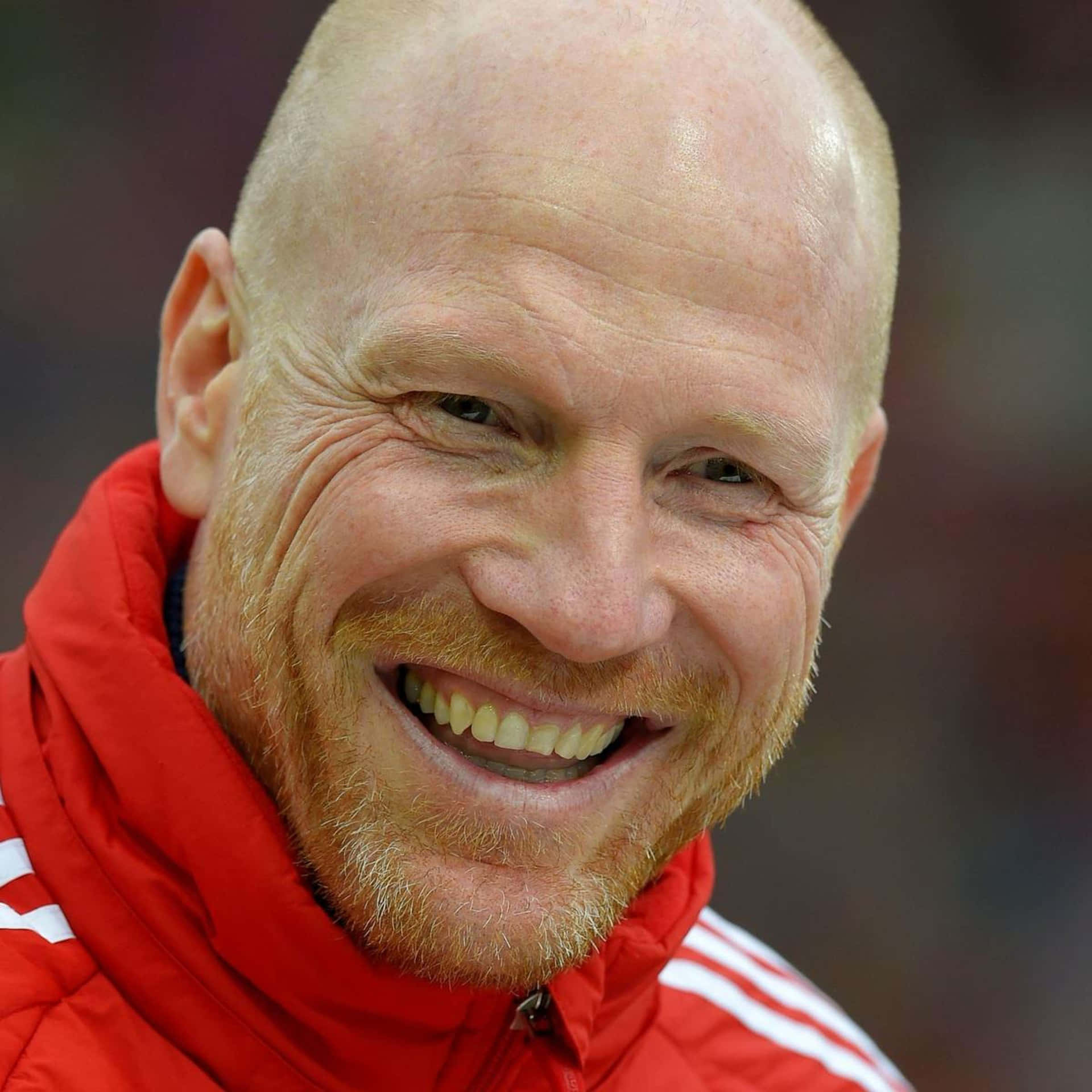 Matthias Sammer Adorning A Red Jacket With White Stripes Background
