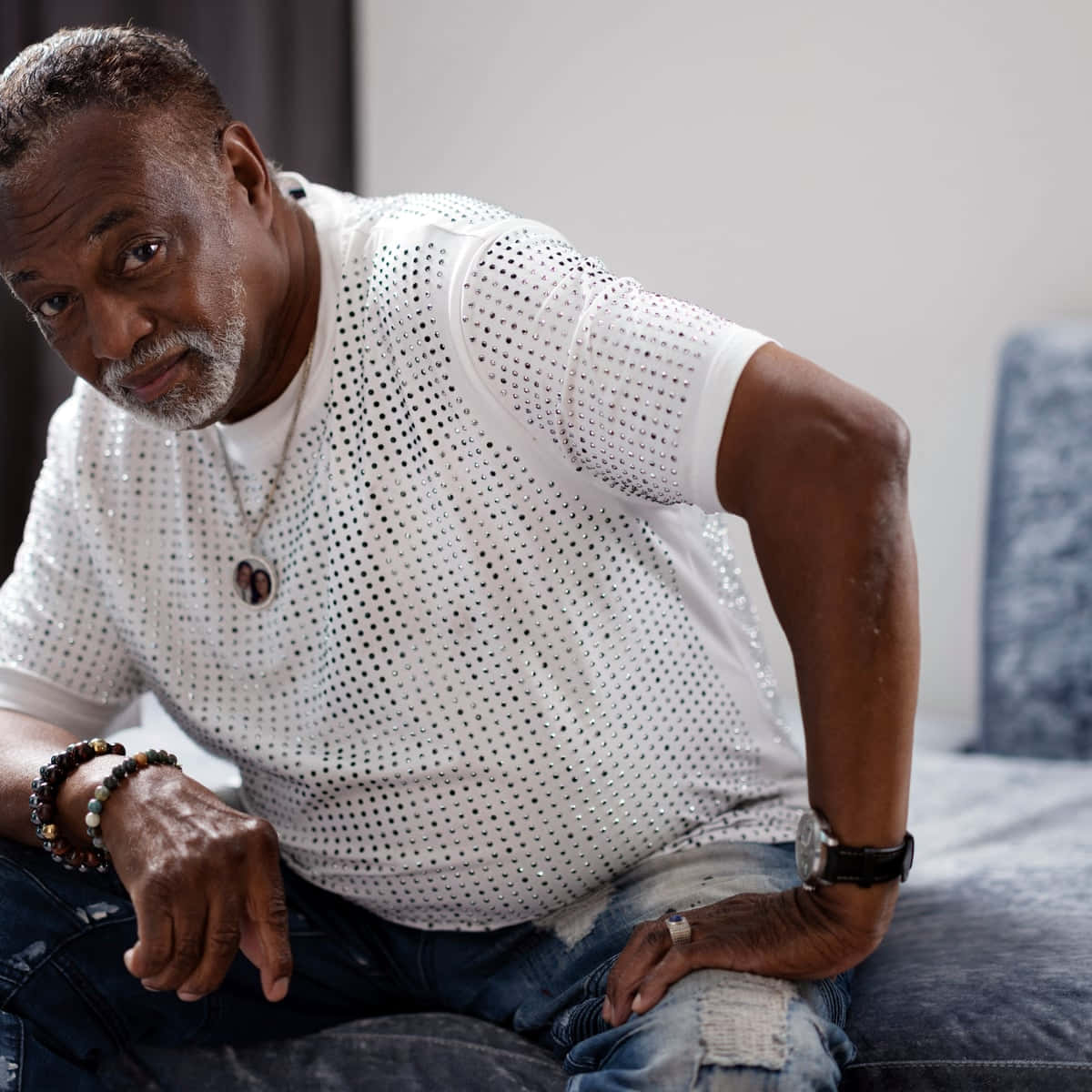 Mature Manin White Shirt Leaningon Couch Background