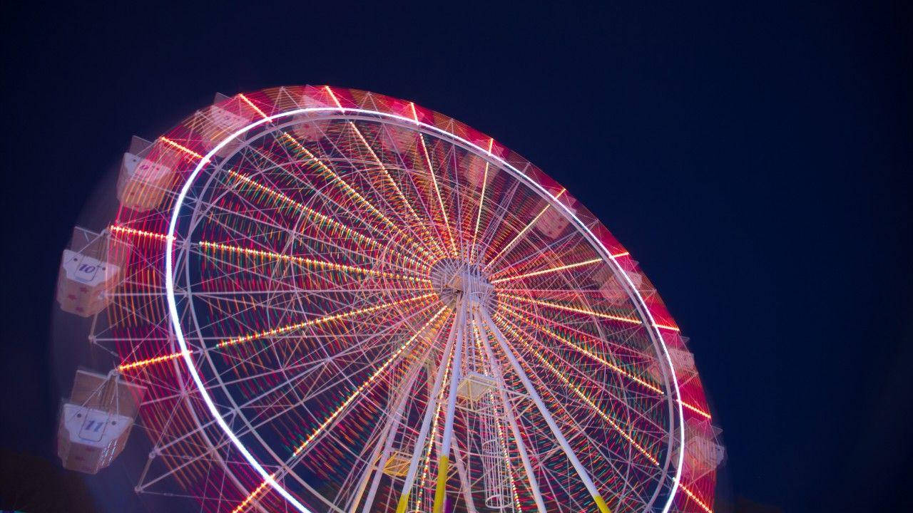 Mesmerizing Display Of Neon Lights On Ferris Wheel Background