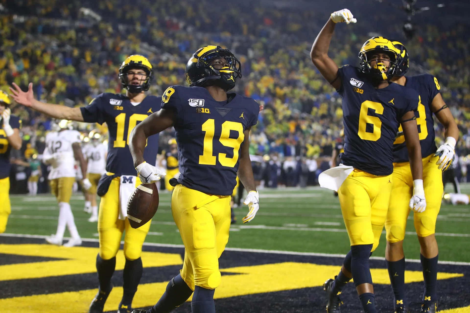 Michigan Wolverines Football Players Celebrate After A Touchdown Background
