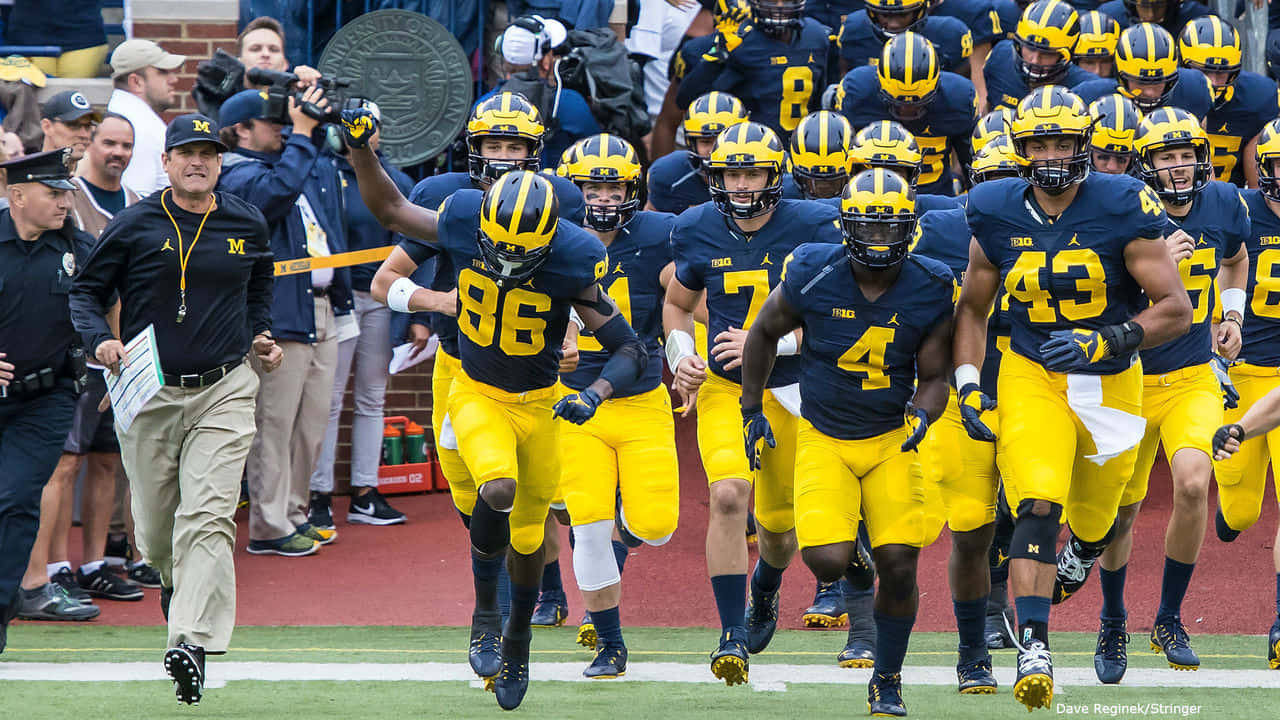 Michigan Wolverines Football Team Running Onto The Field Background