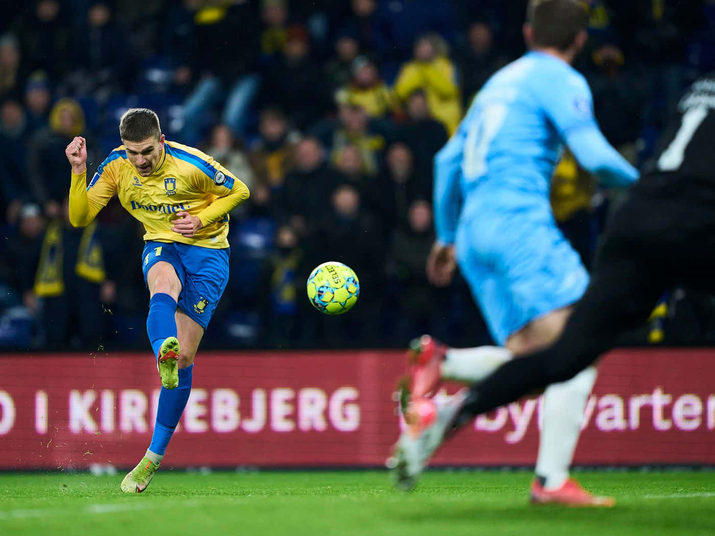 Mikael Uhre Kicking Yellow Ball Background