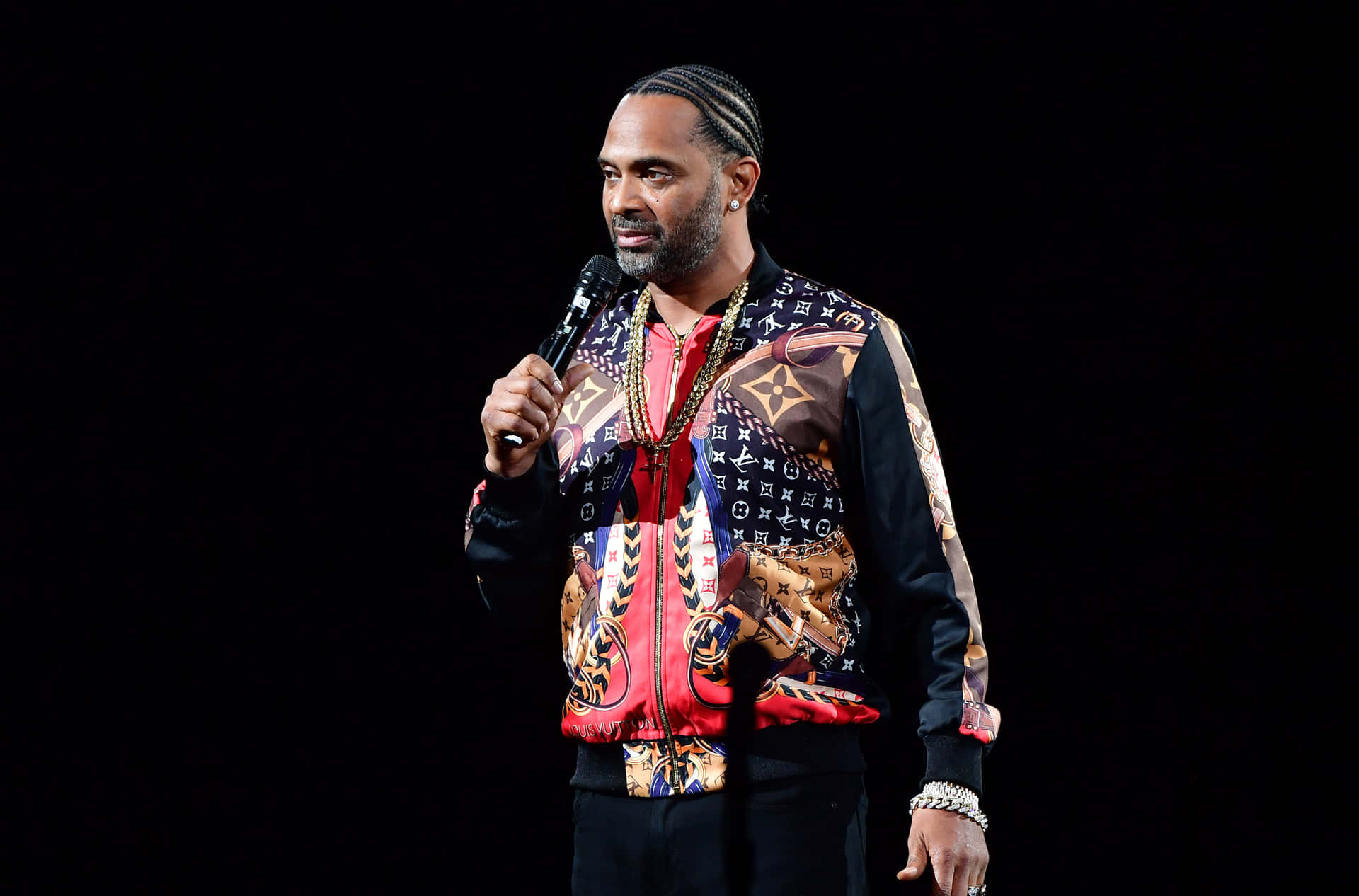 Mike Epps Strikes A Thoughtful Pose Against A Textured Grey Wall Backdrop. Background