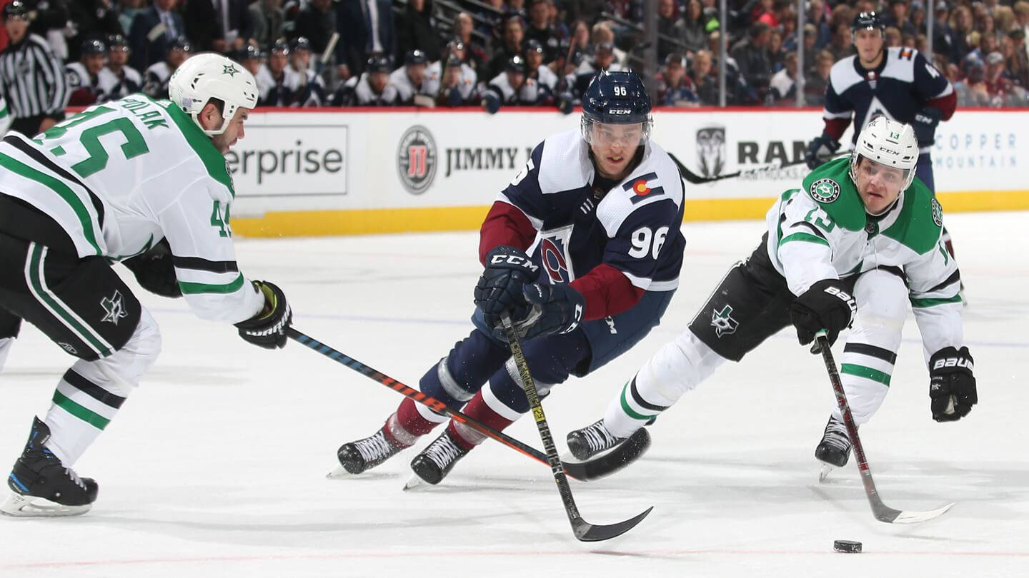 Mikko Rantanen Dribbling Hockey Puck Against Dallas Stars Players Background