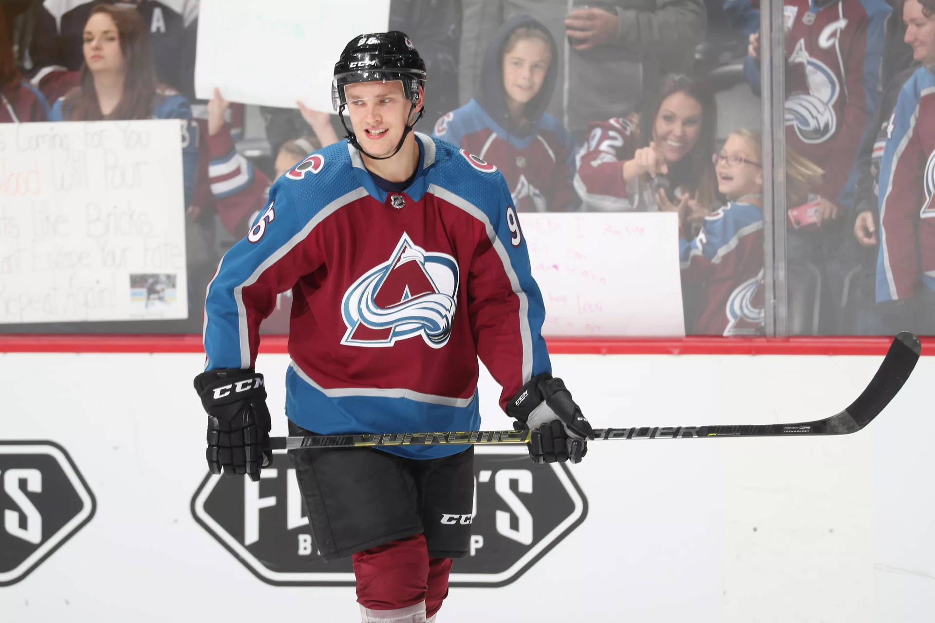 Mikko Rantanen Holding Hockey Stick With Both Hands While Smiling Background