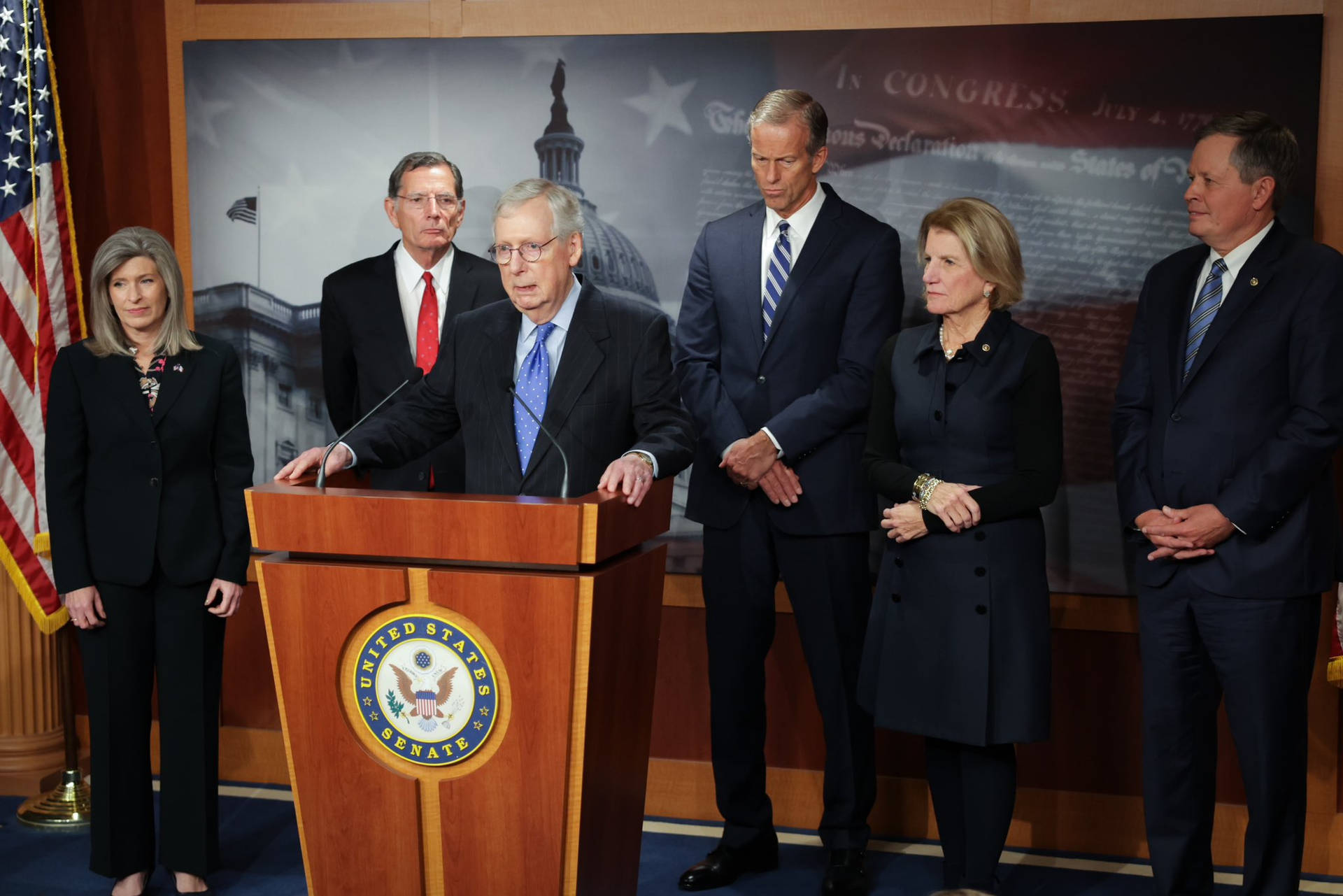 Mitch Mcconnell Critiquing Policies During A News Conference Background