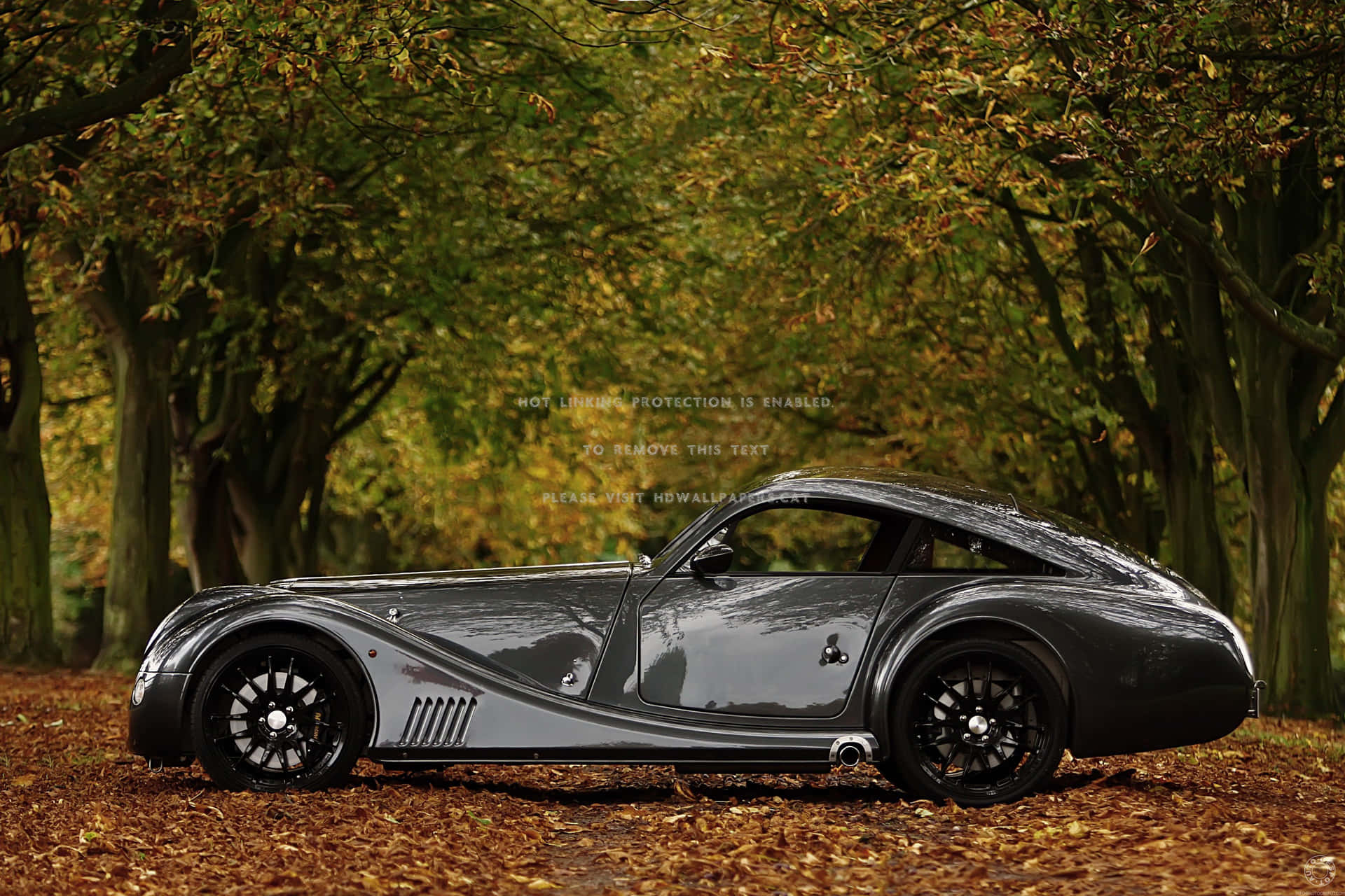 Modern Morgan Sports Car On A Picturesque Road Background