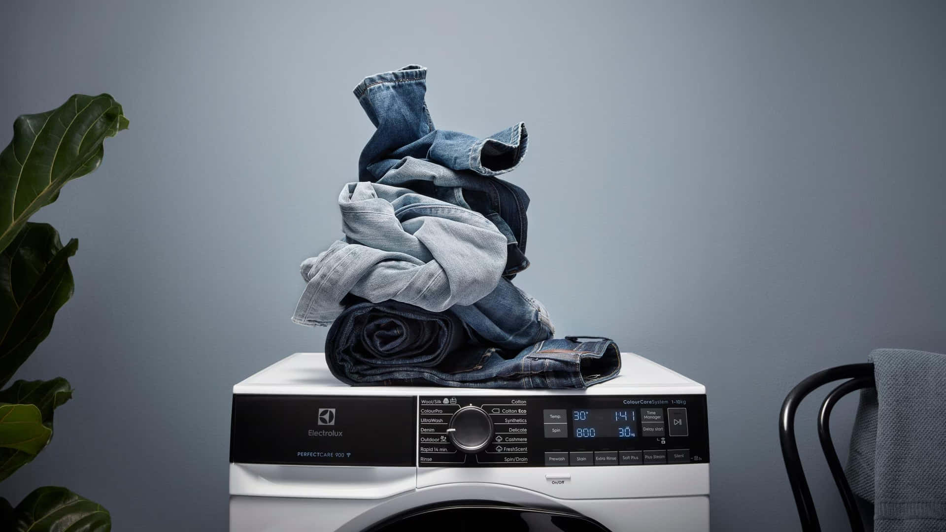 Modern Washing Machine With Stacked Jeans Background