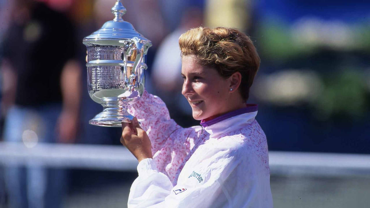 Monica Seles Triumphantly Holding Her Trophy Background