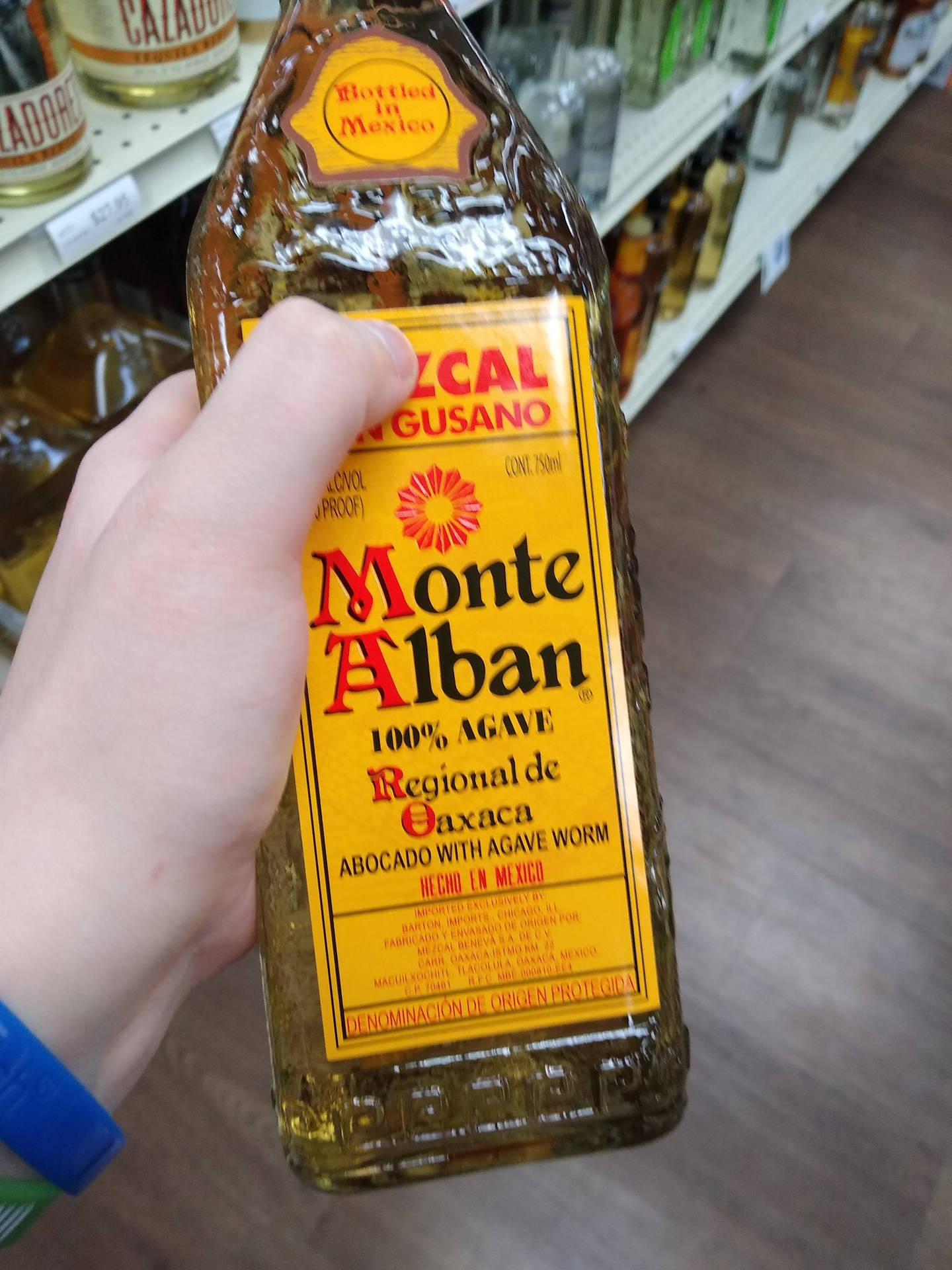 Monte Alban Mezcal Tequila Held By Hand Background