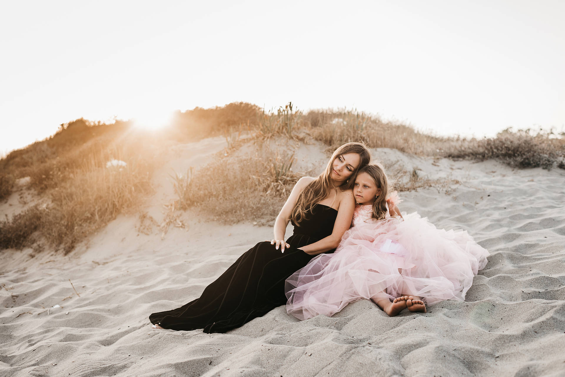 Mother And Daughter Sitting By The Beach