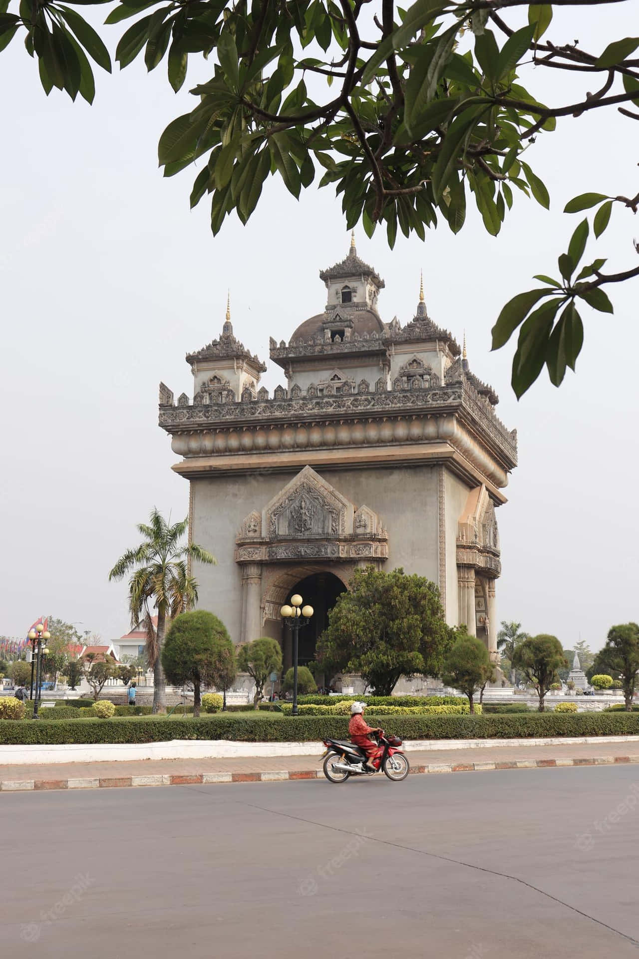 Motorcycle Passing By Patuxai Monument Background
