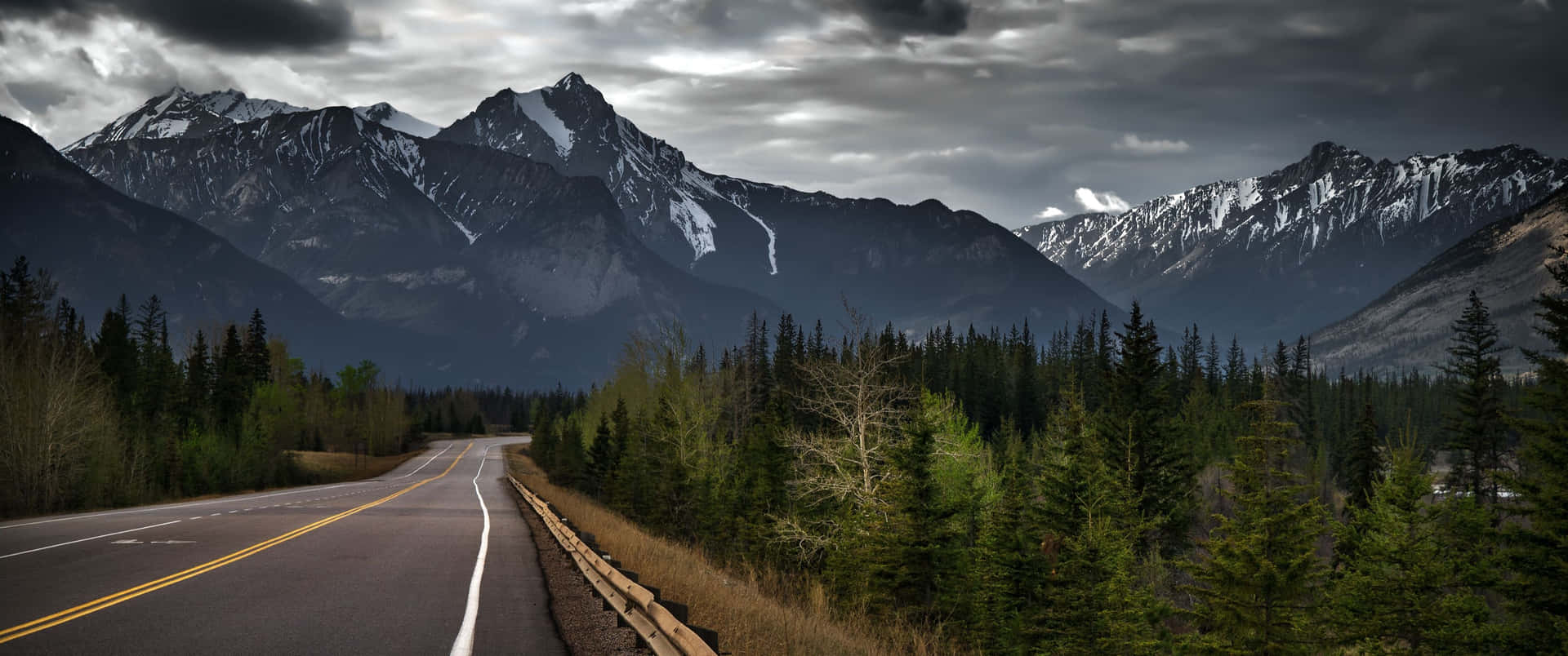 Mountain_ Road_ Under_ Stormy_ Skies Background