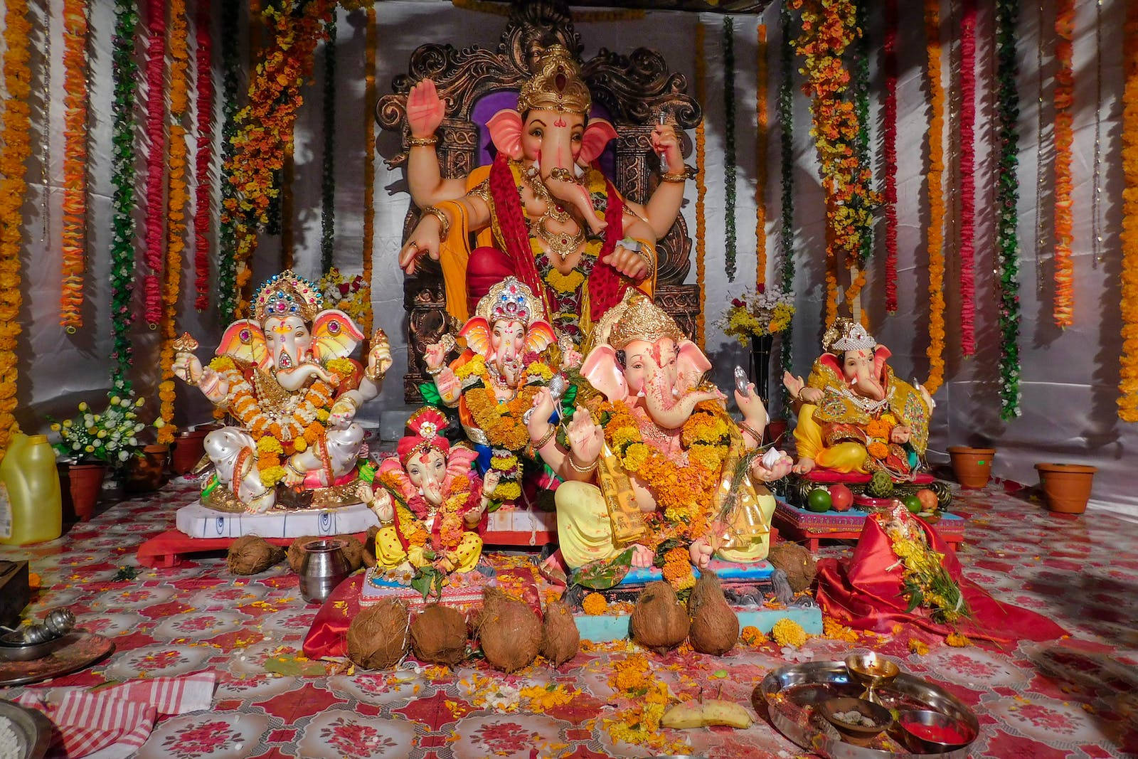 Multiple Vinayaka Statues With Offerings Background