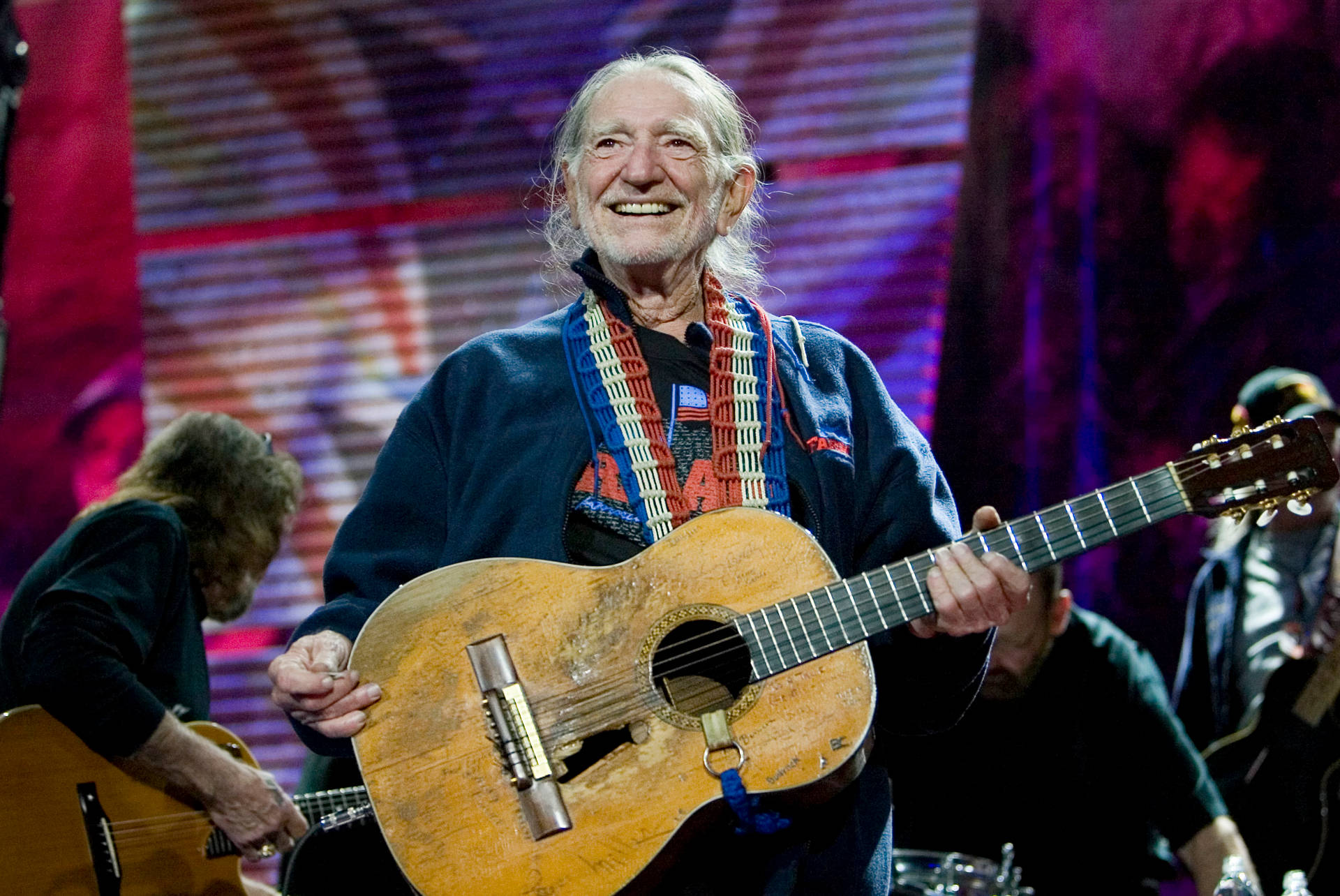 Musician Willie Nelson Smiling During Concert Background