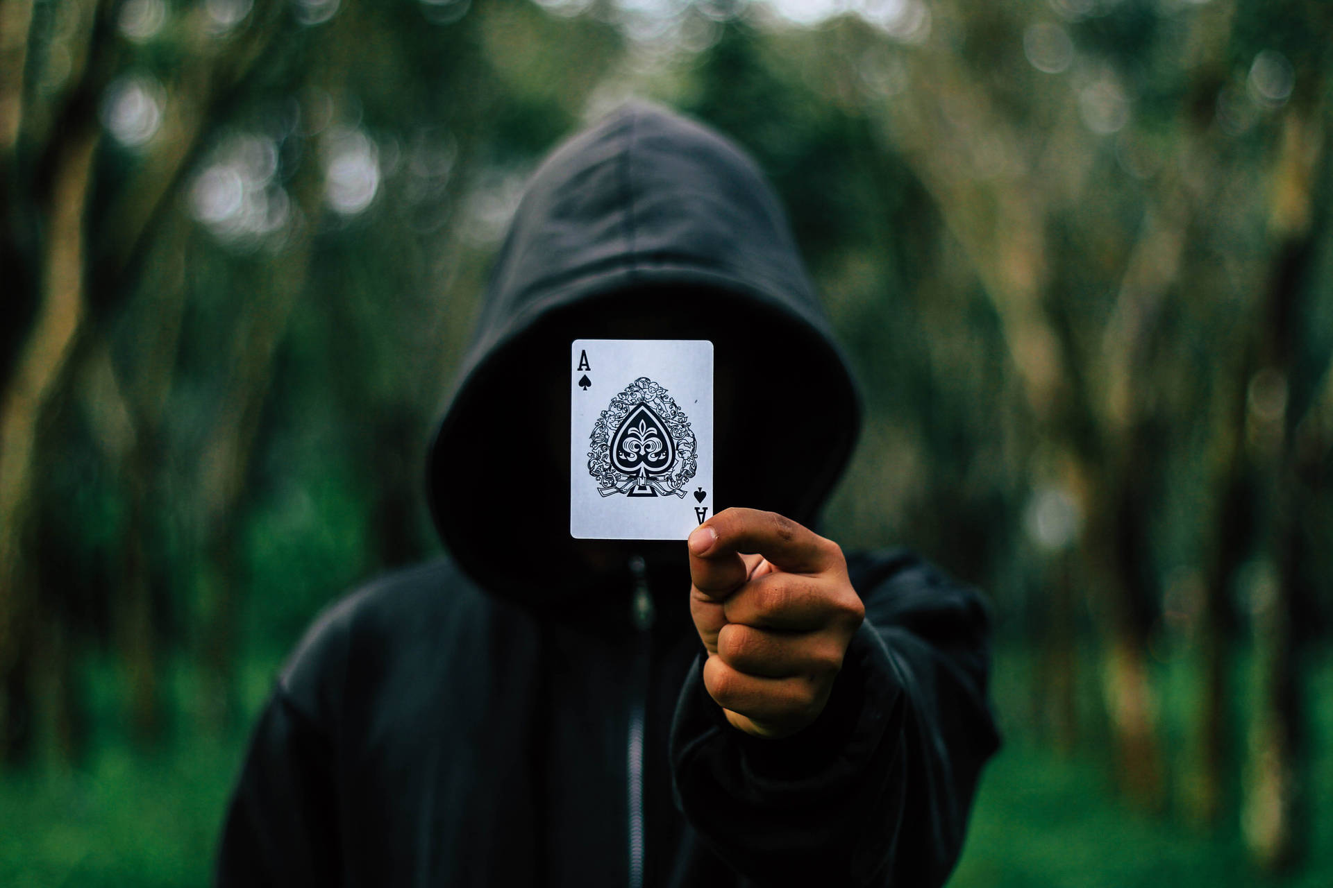 Mysterious Hooded Figure Engrossed In A Card Game Background