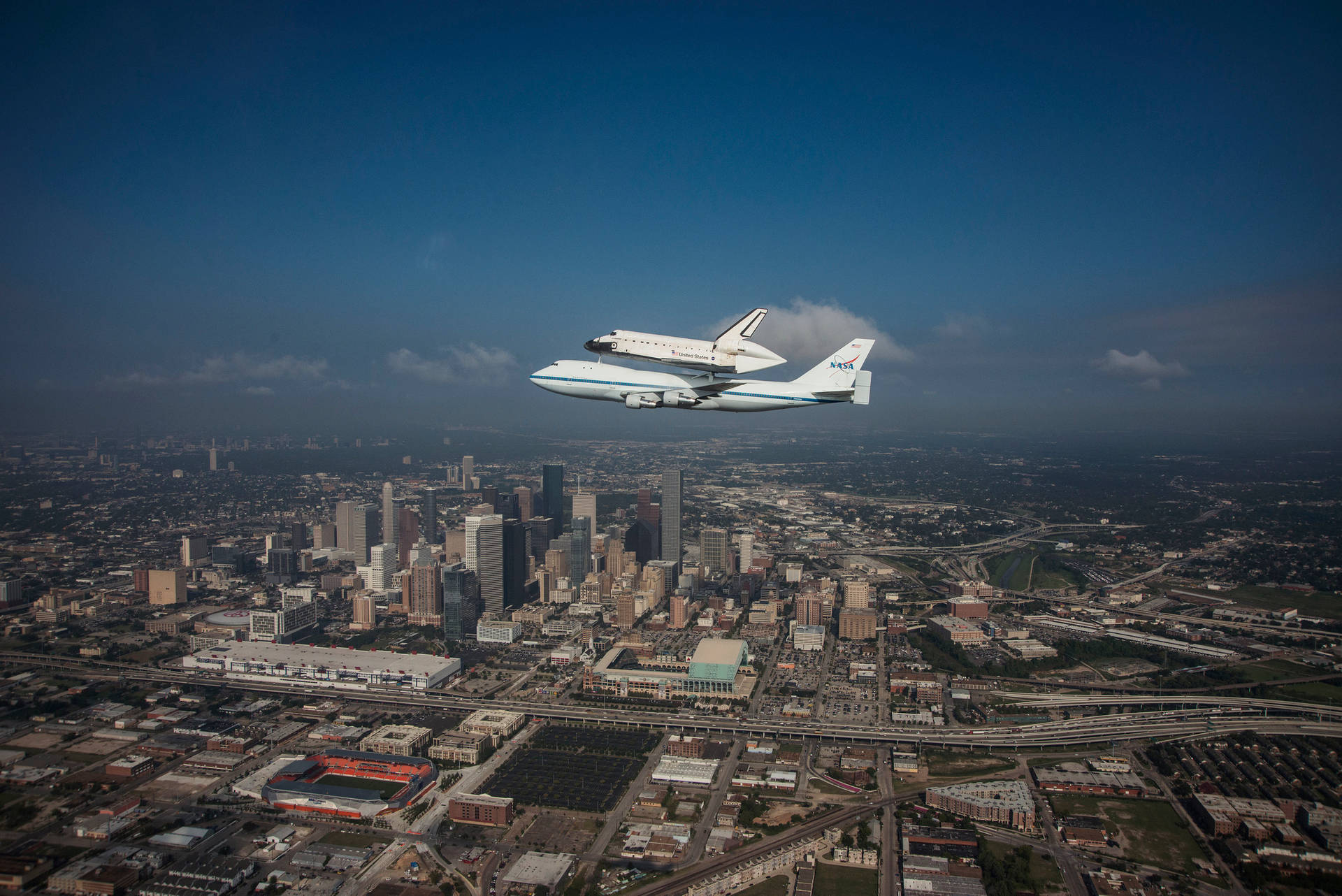 Nasa Houston Aircrafts Flying Over City Background