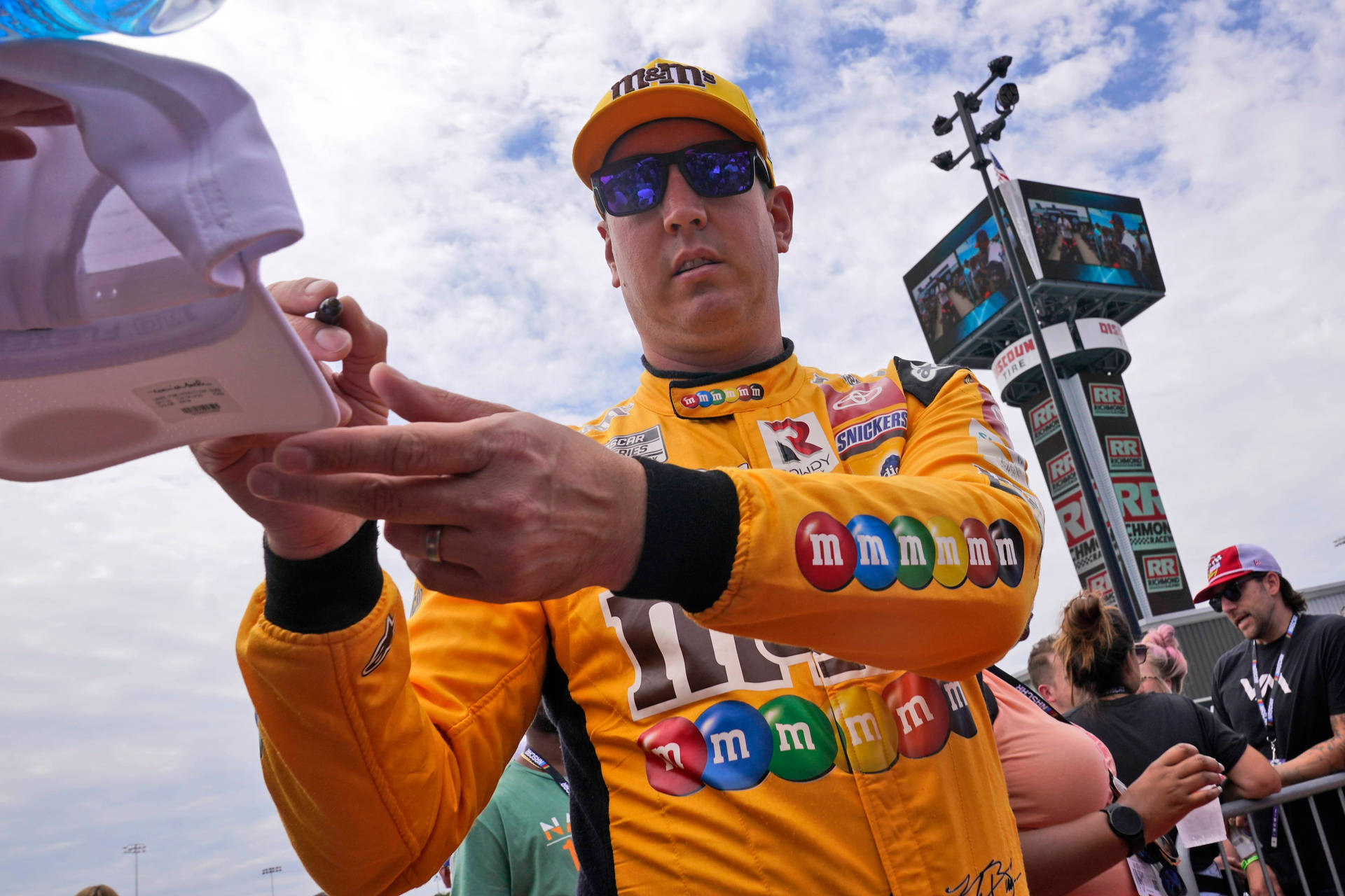 Nascar Champion Kyle Busch Autographing A Fan's Cap Background