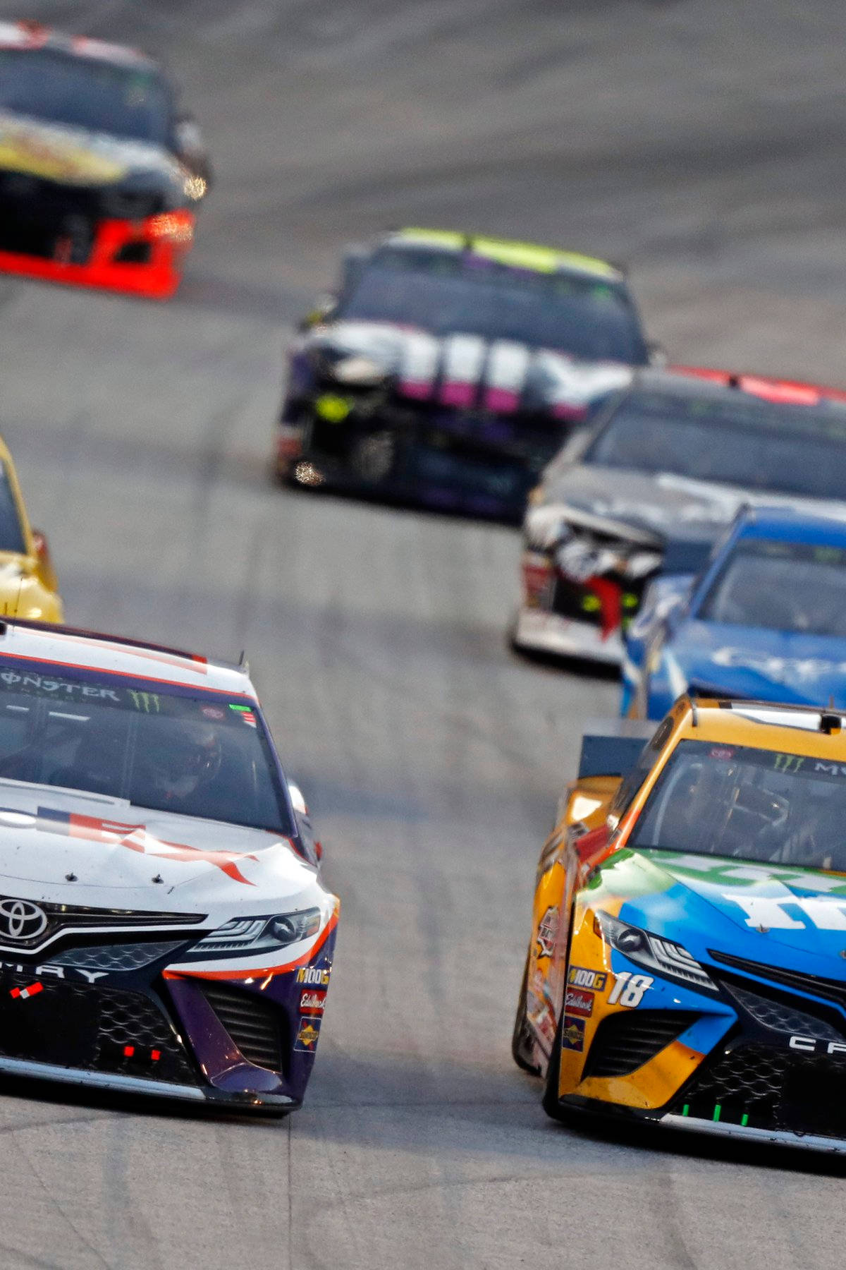 Nascar Legend Denny Hamlin Leading The Speed In Intense Racing Battle Background