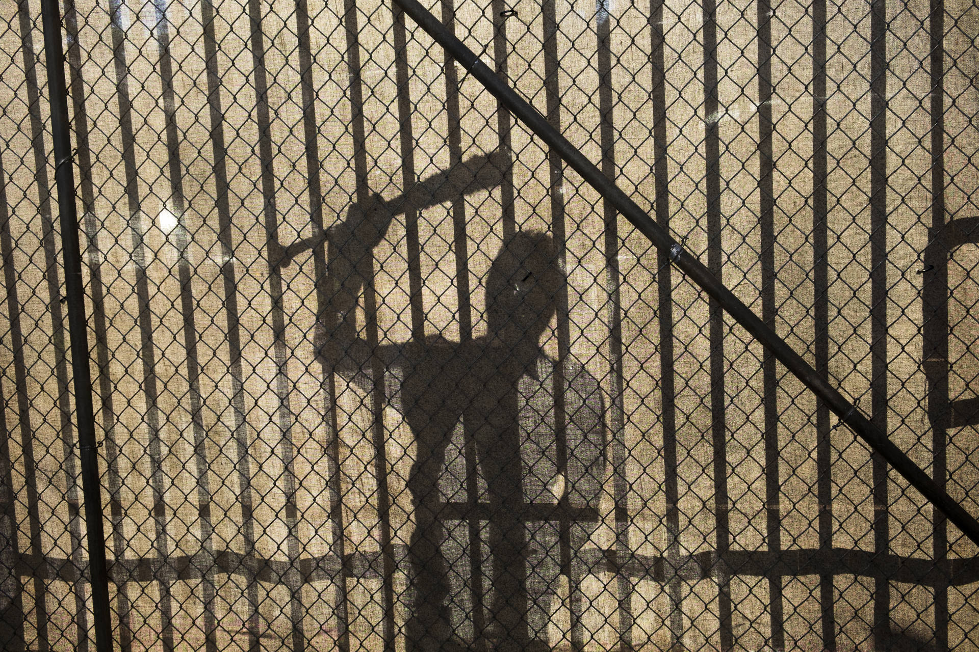 Negan's Shadow Against A Fence Background