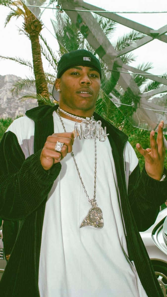 Nelly Proudly Holding Silver Pendant With His Name Background