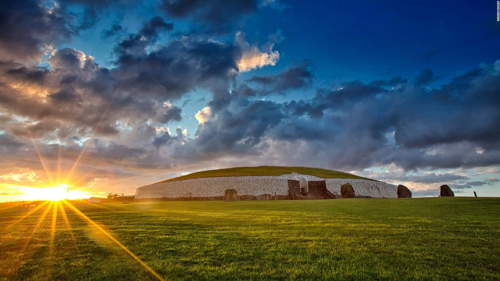 Newgrange Against The Blue Sky With Sunset Background