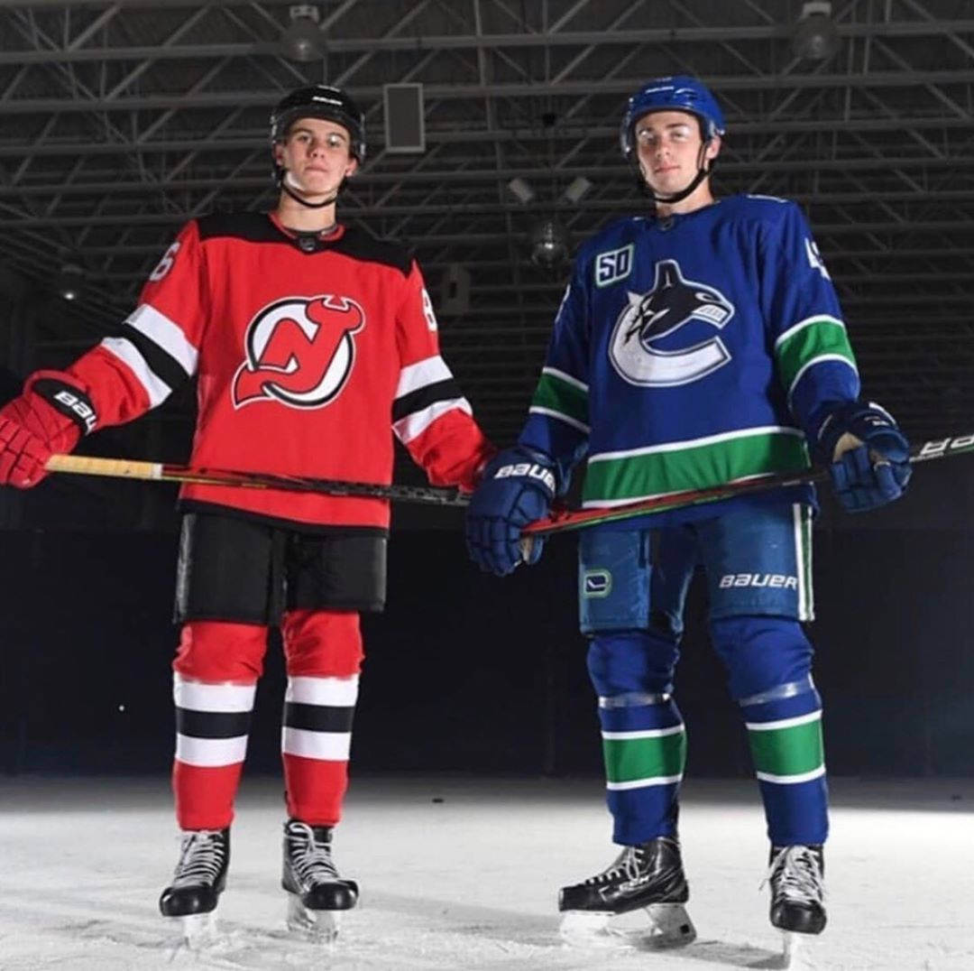 Nhl Stars Quinn Hughes And Jack Hughes Posing On Ice Rink Background