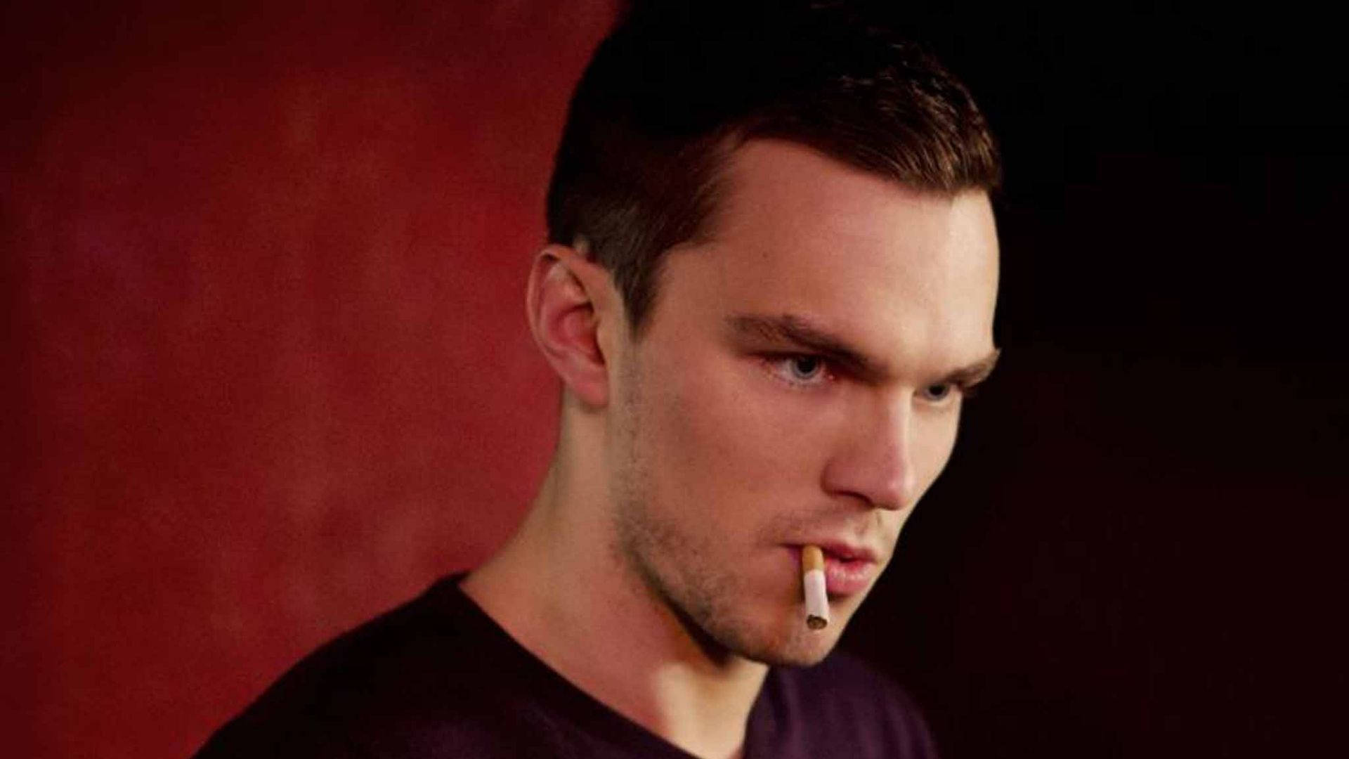 Nicholas Hoult Capturing A Rugged, Relaxed Moment With A Cigarette Background