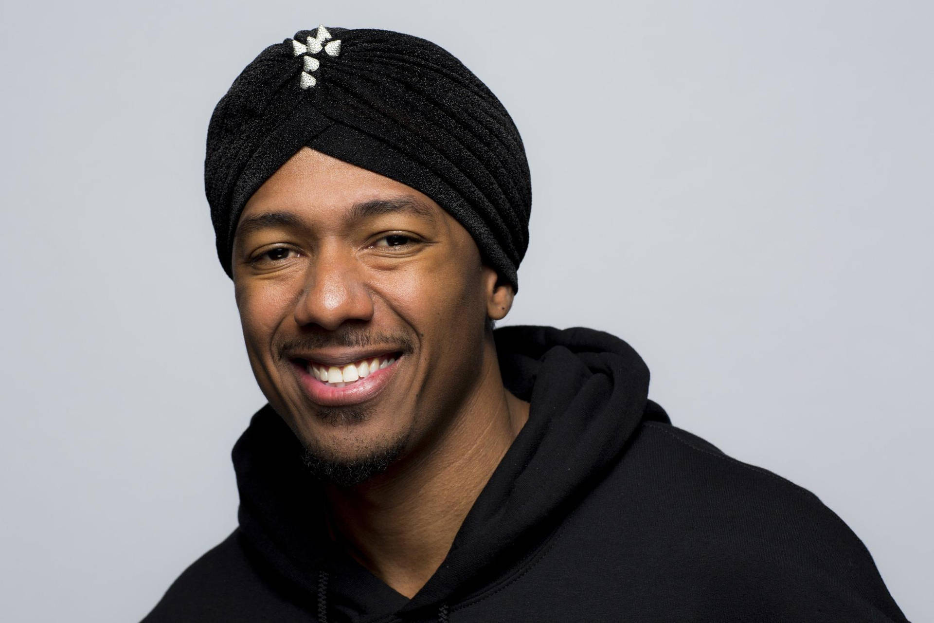 Nick Cannon Posing With Black Turban Background