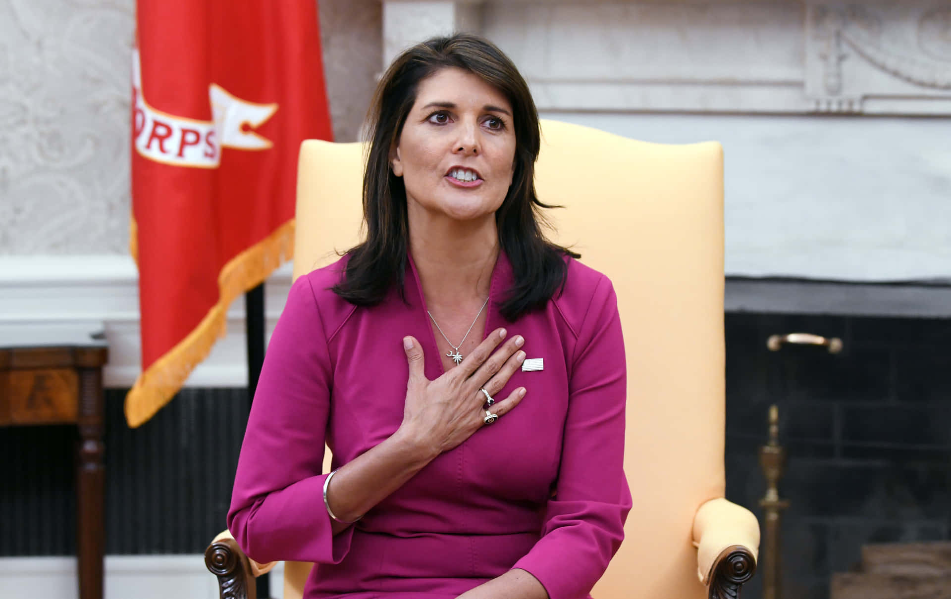 Nikki Haley With Her Hand On Her Chest Background
