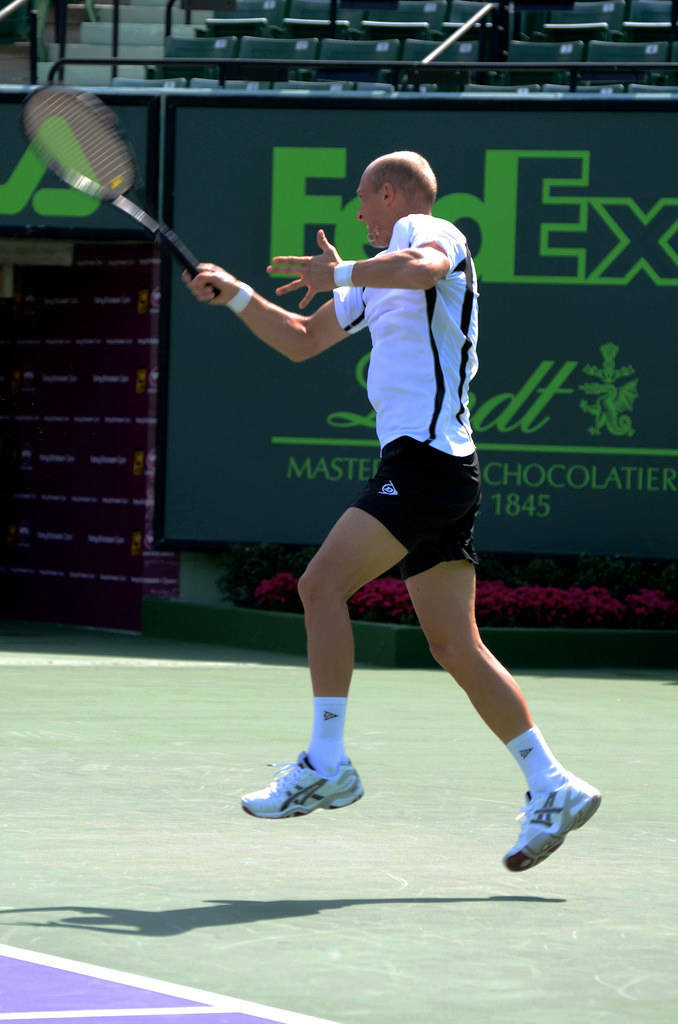 Nikolay Davydenko Executes A Sprinting Backhand On A Tennis Court Background