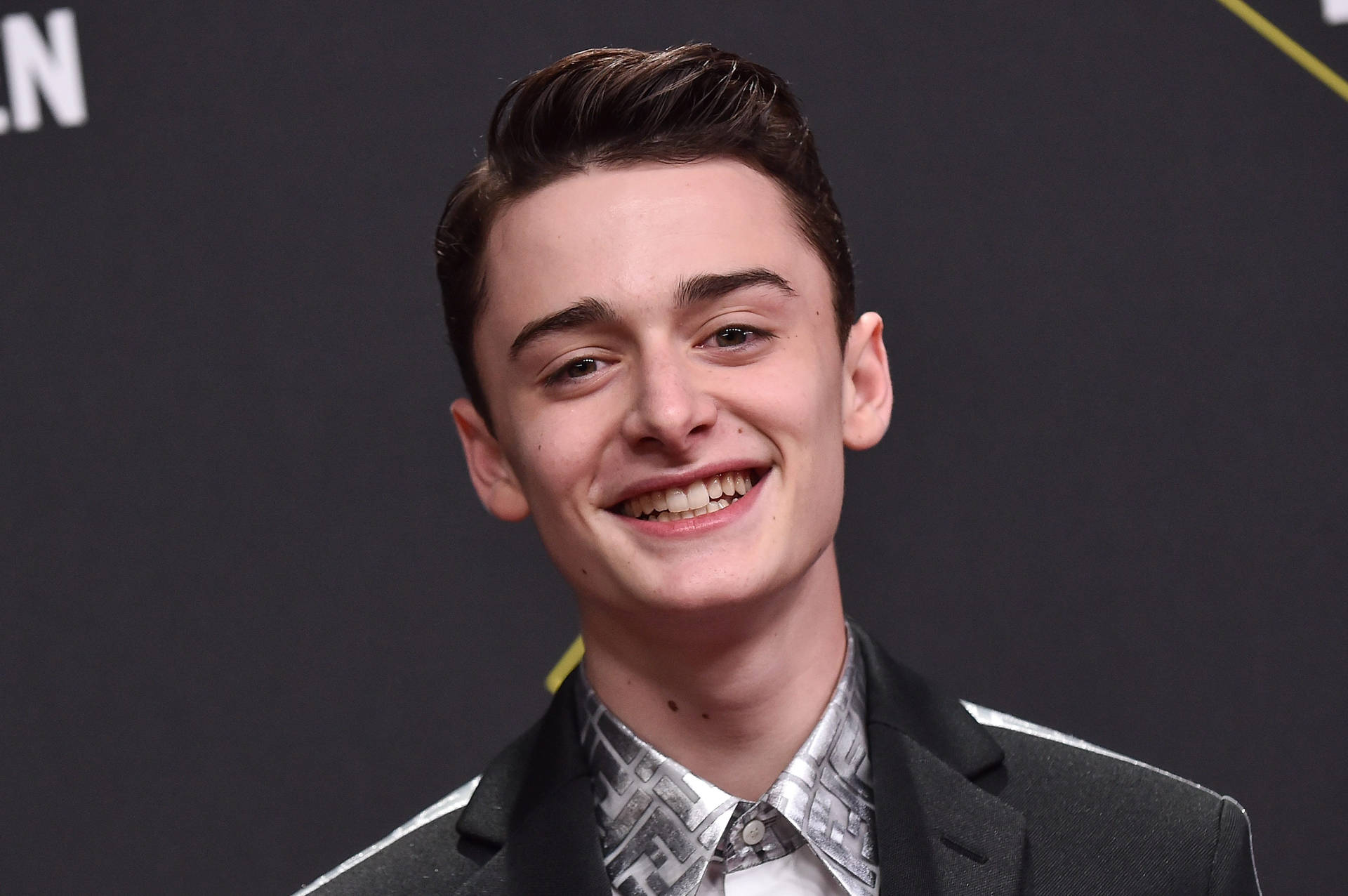 Noah Schnapp Smiling Against Dark Backdrop