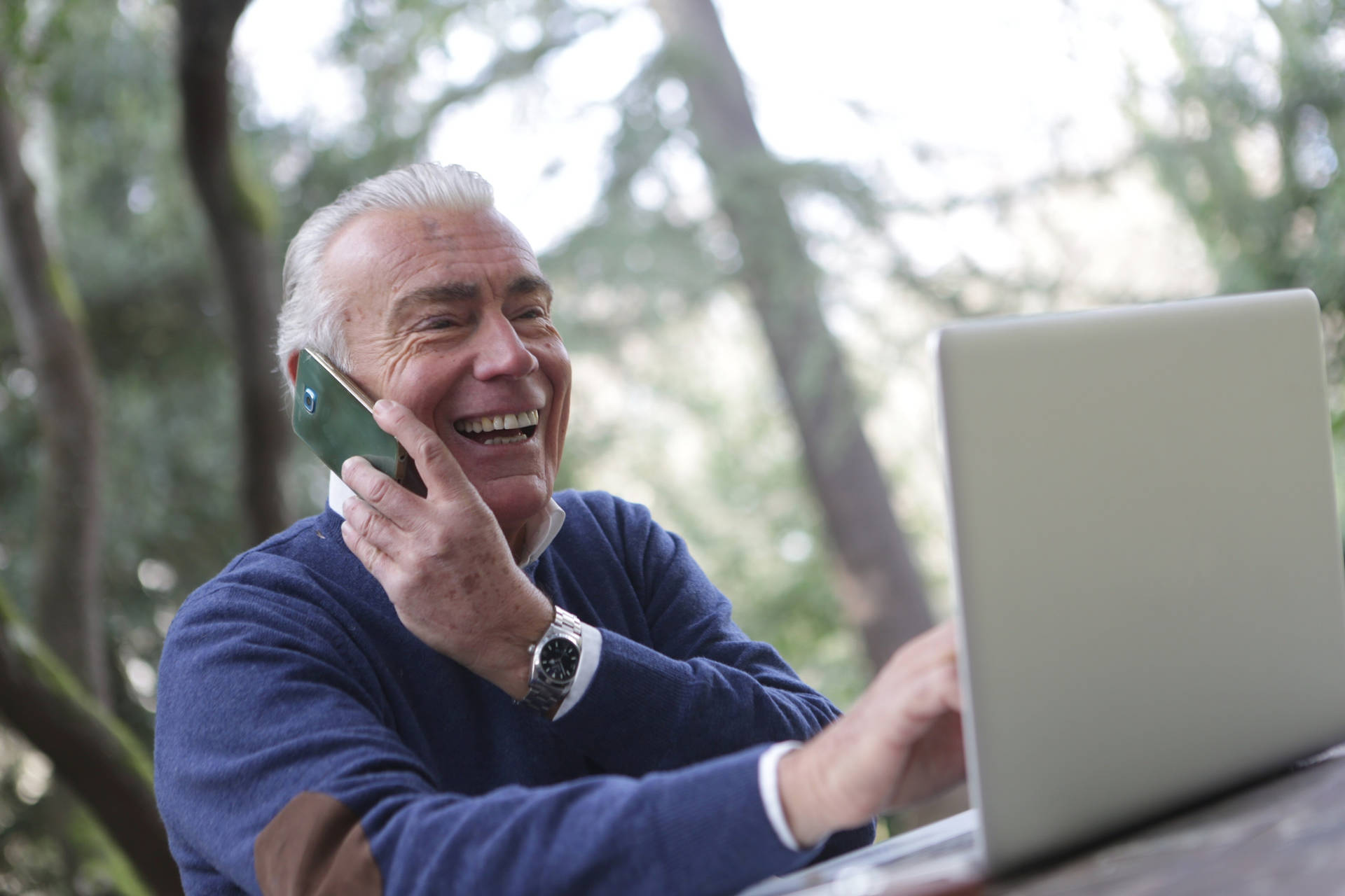 Old Man Laughing On Laptop And Phone Background