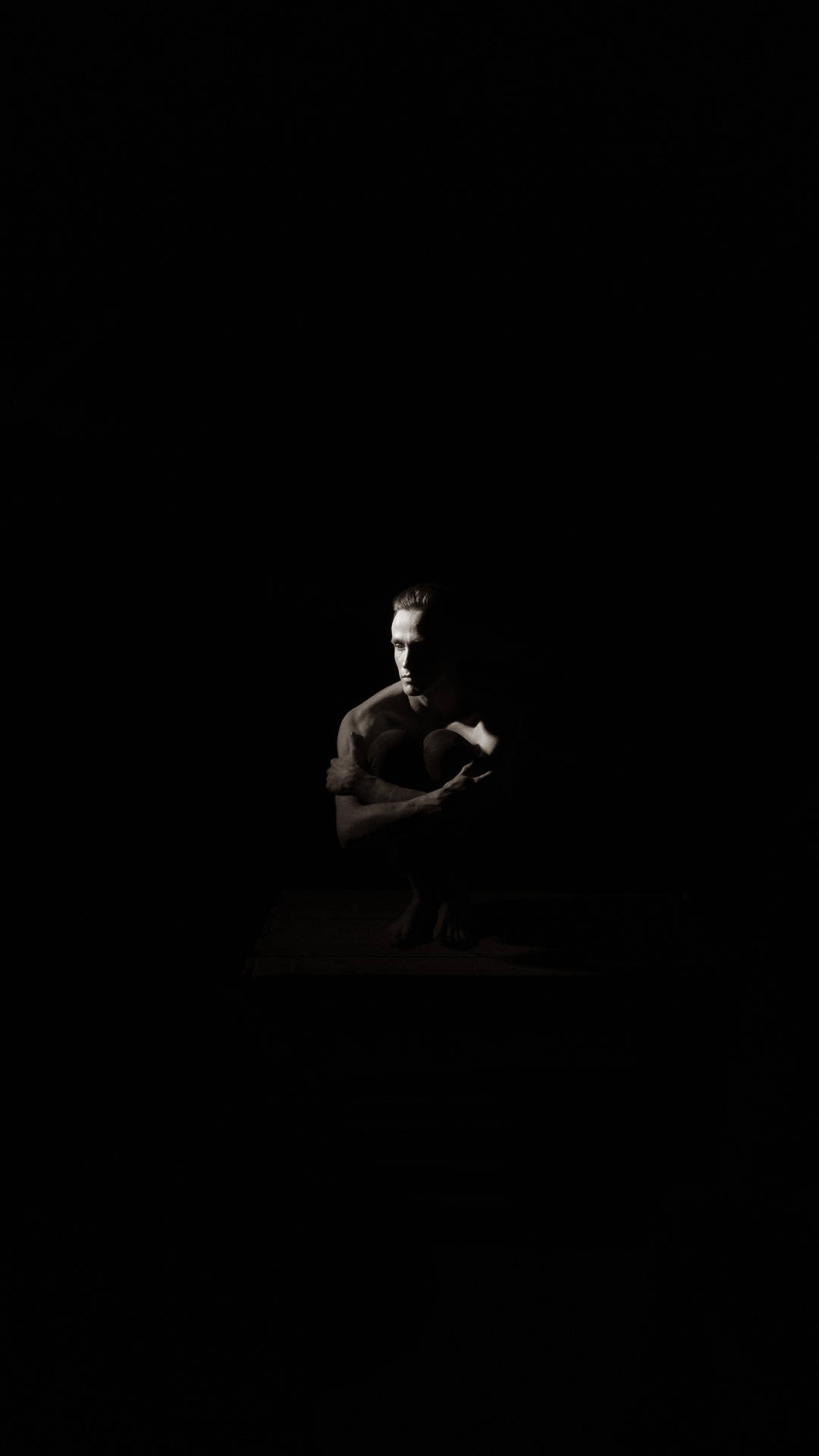 Ominous Man Sitting In The Dark Background