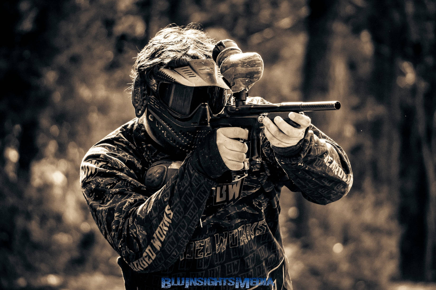 Paintball Player Aiming In The Woods Background