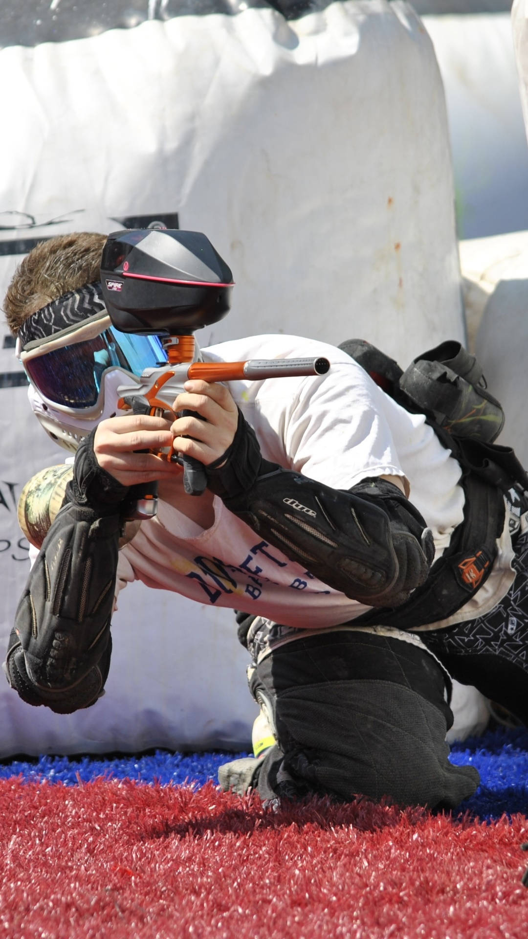 Paintball Player Leaning On Red And Blue Turf Background