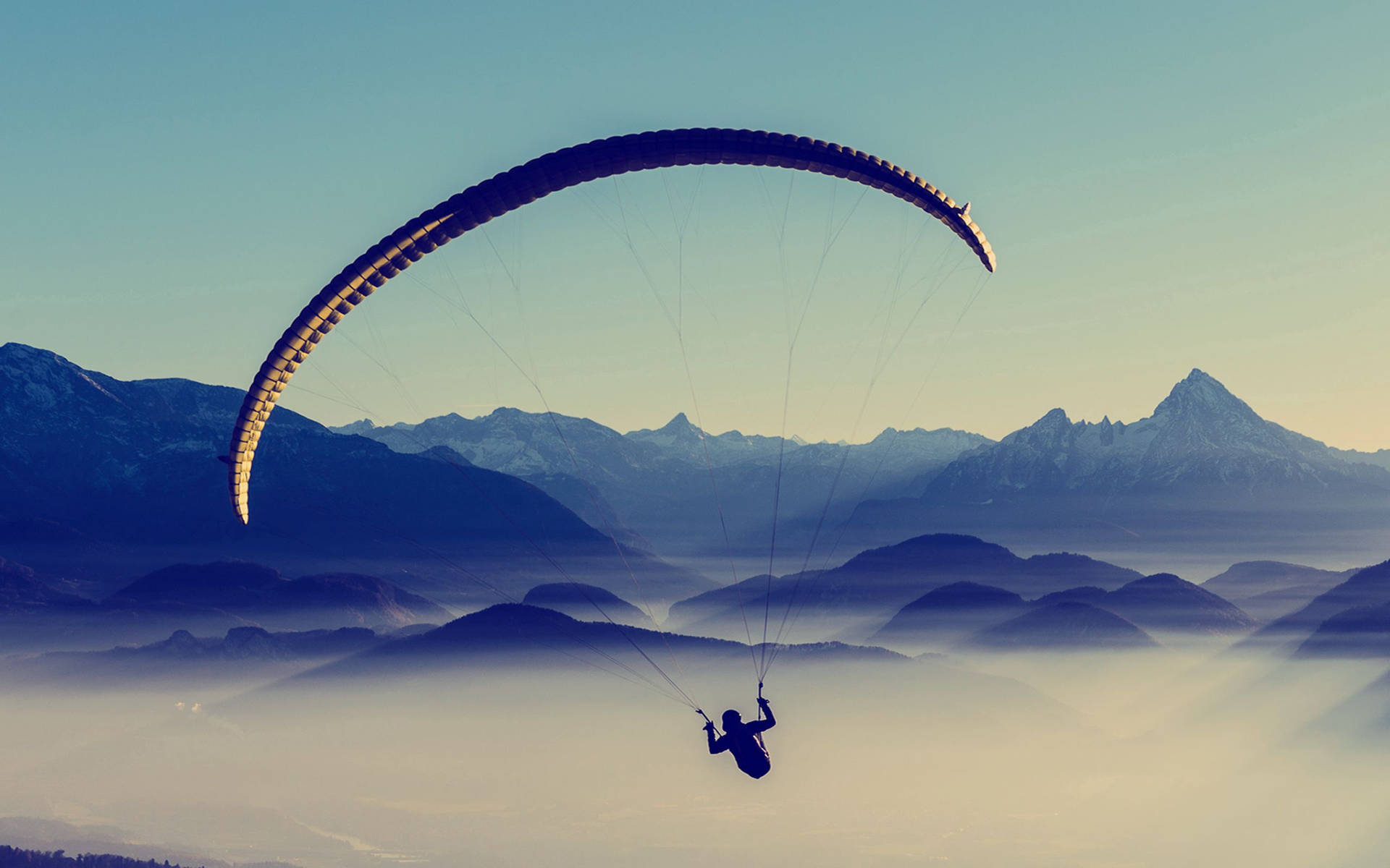 Paragliding Above Cloud-covered Mountains Background