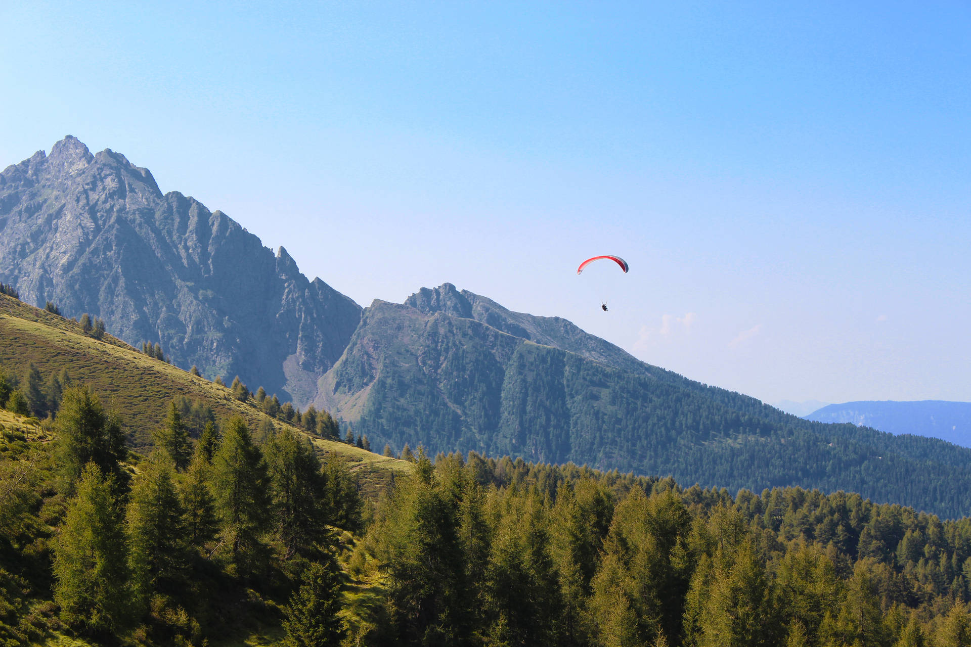Paragliding Above Forested Hills Background