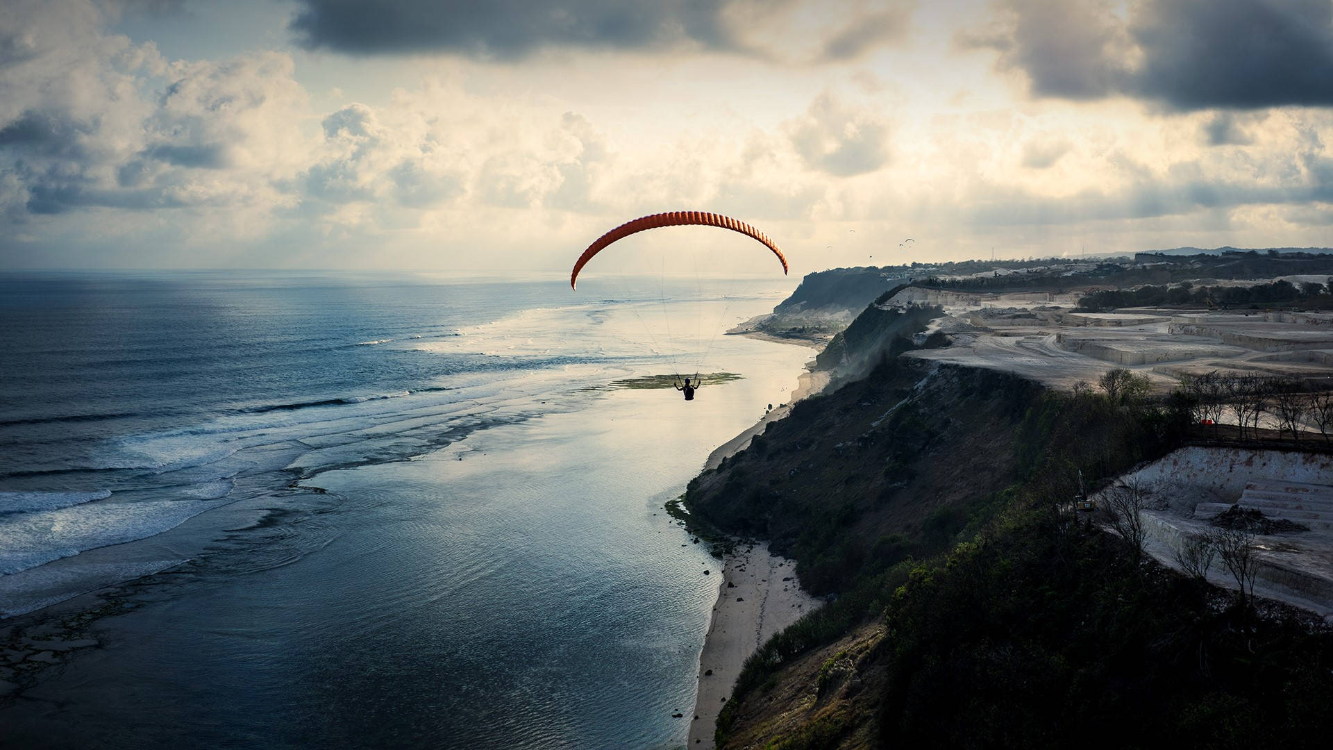 Paragliding Near A Cliffside Beach Background