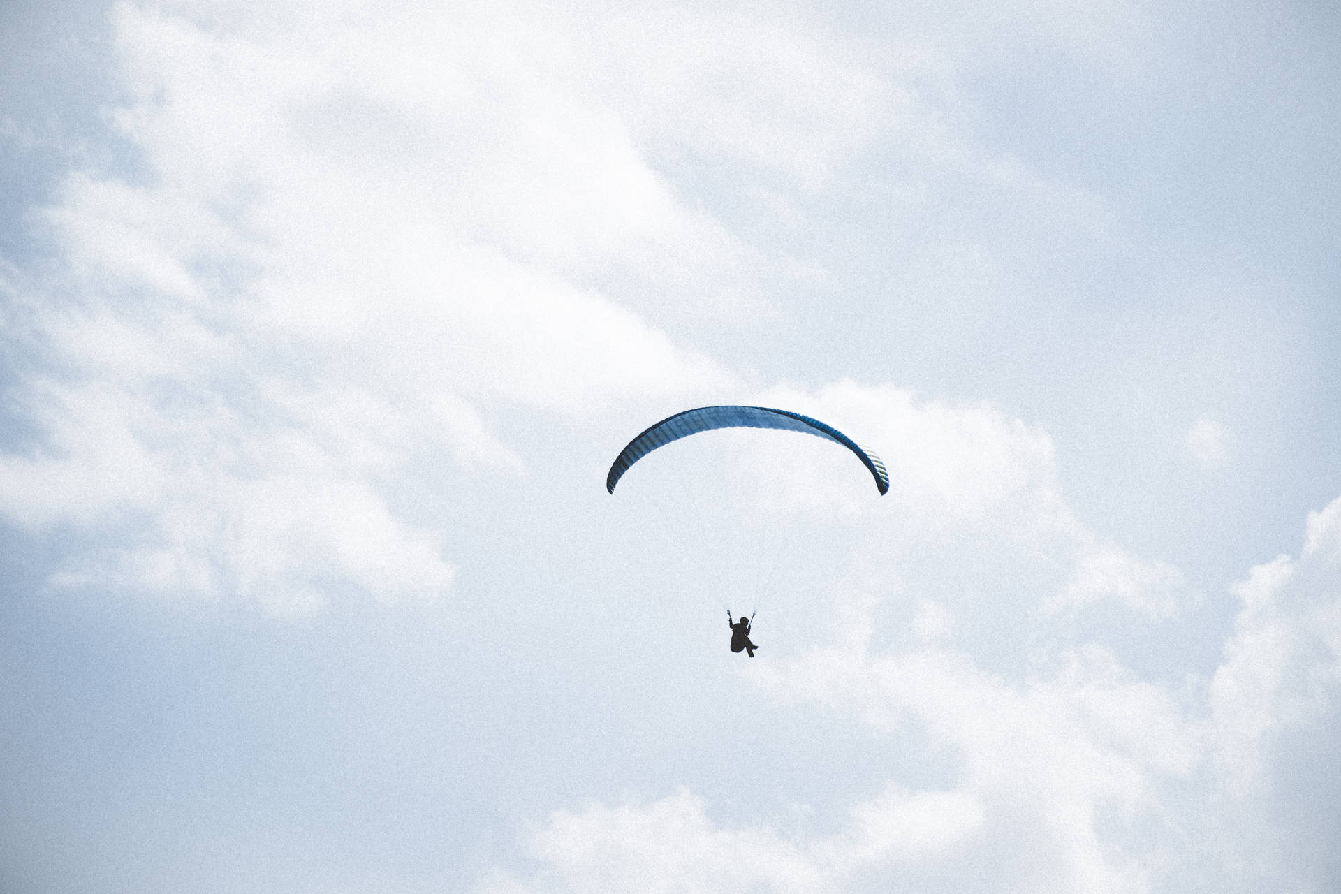 Paragliding Pilot Amongst The Clouds Background